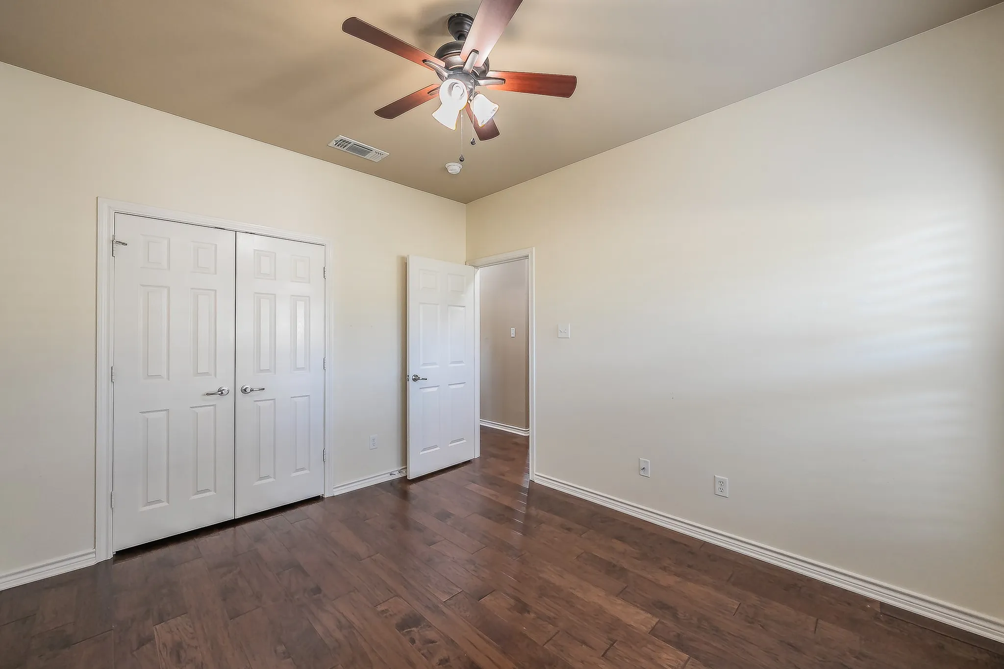 Expansive wood-finish flooring complemented by a ceiling fan with integrated lighting