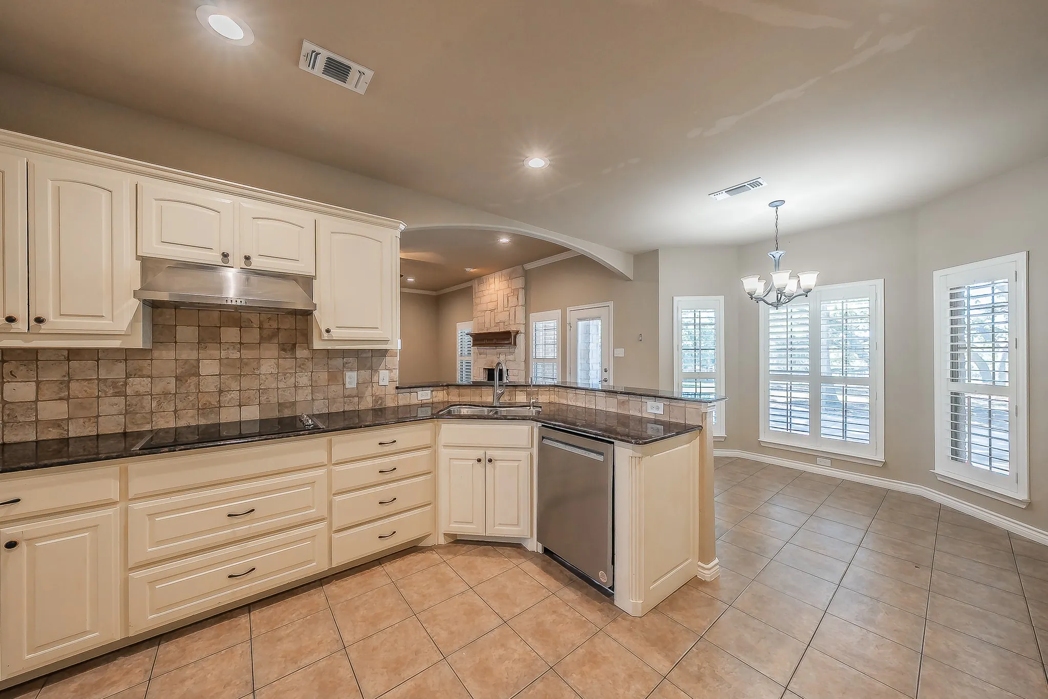 Kitchen featuring cream-colored cabinetry, tile backsplash, dark countertops, and stainless steel appliances