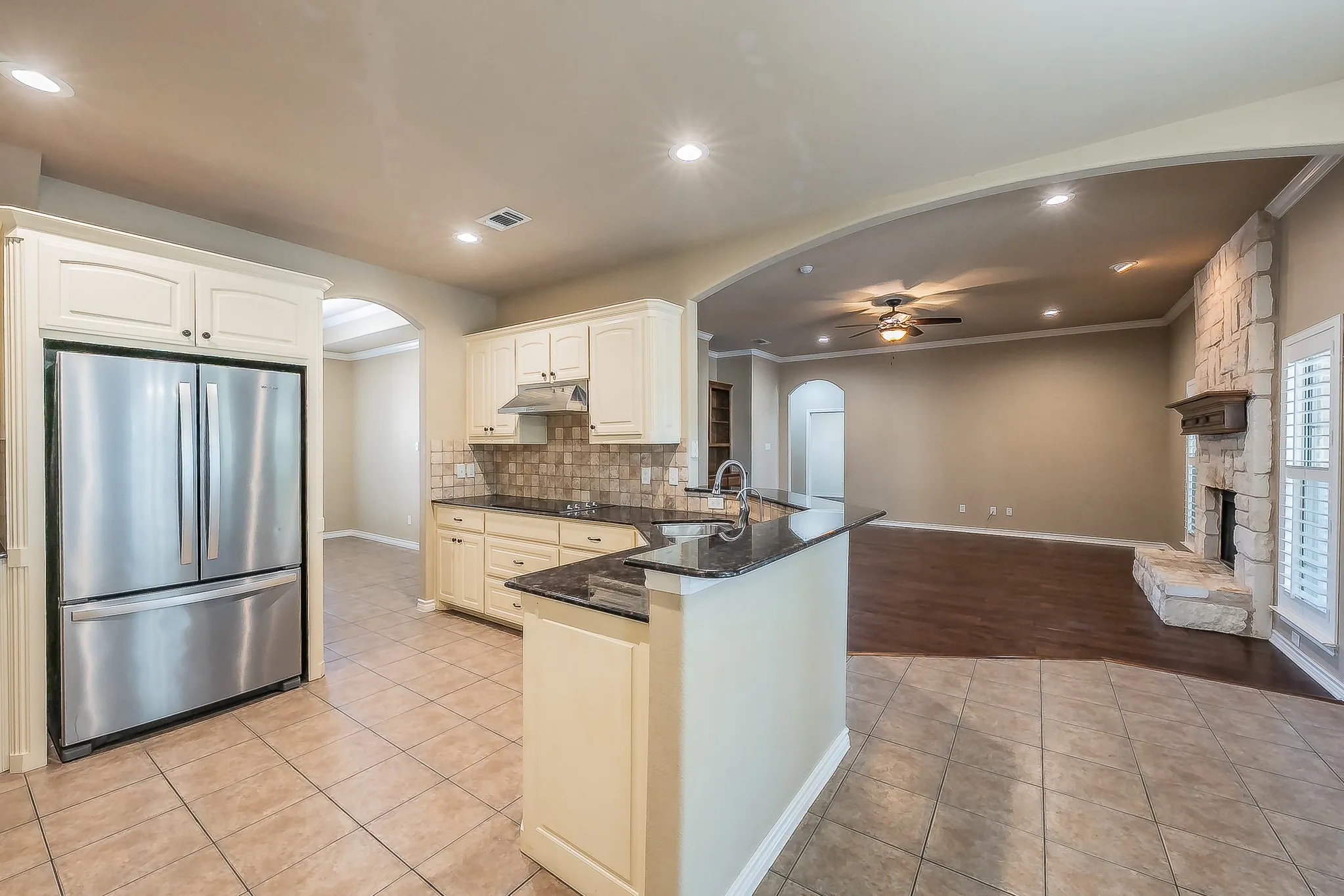 Kitchen featuring cream-colored cabinetry, dark countertops, tiled flooring, and a stainless steel refrigerator