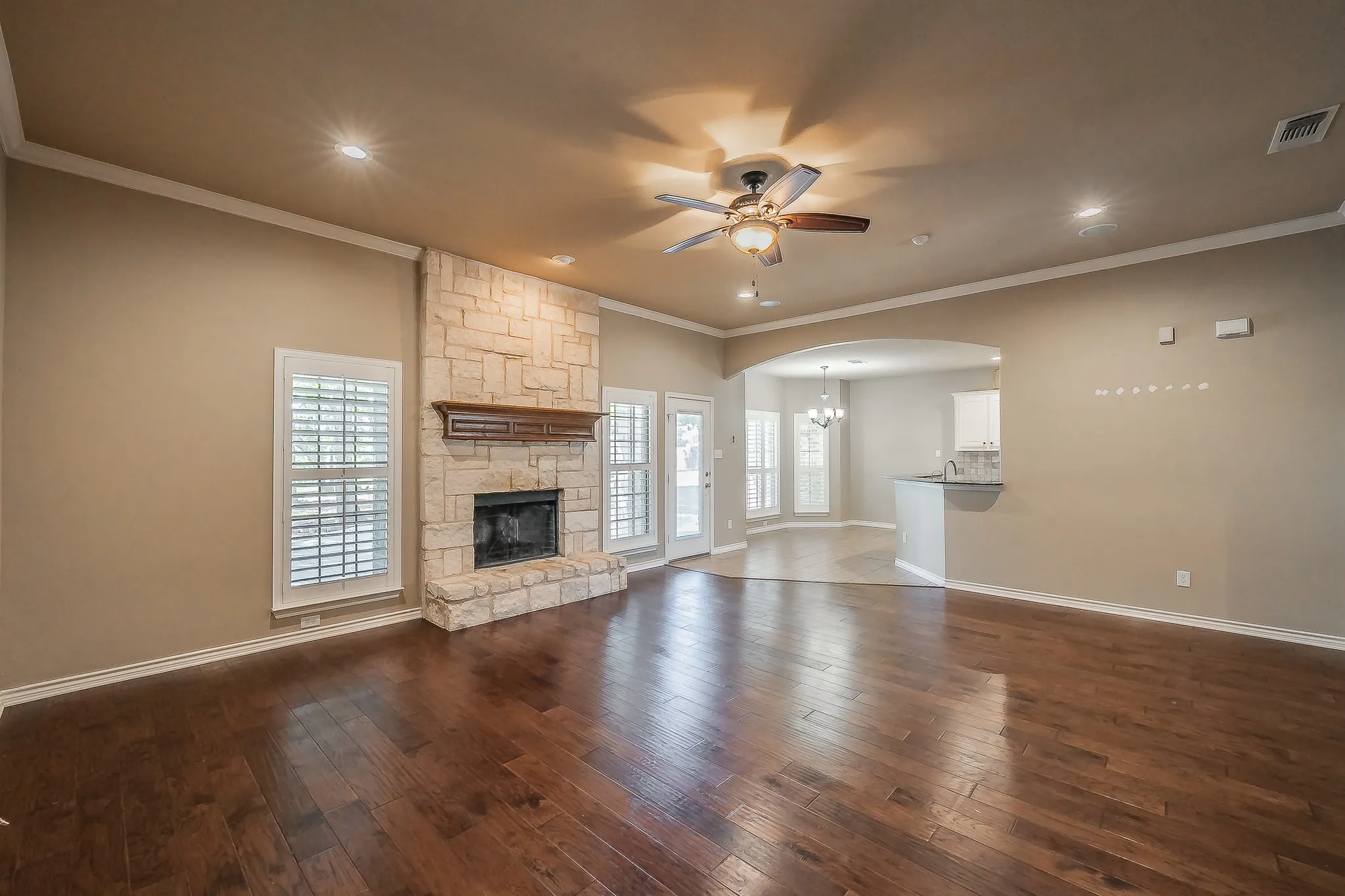 Spacious living area featuring wood-finish flooring, a stone fireplace, recessed lighting, and a ceiling fan