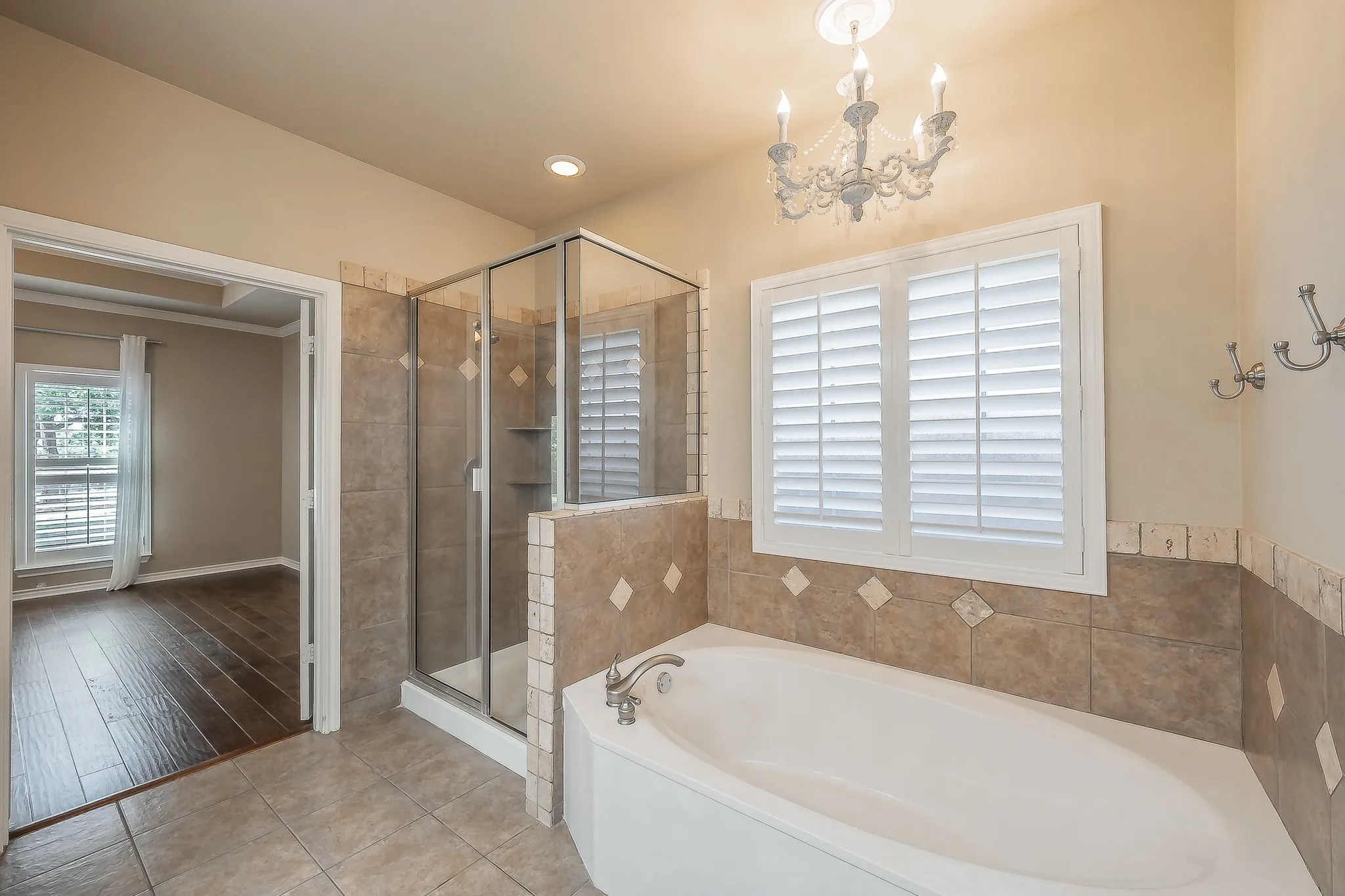 Corner soaking tub with tile surround and white plantation shutters