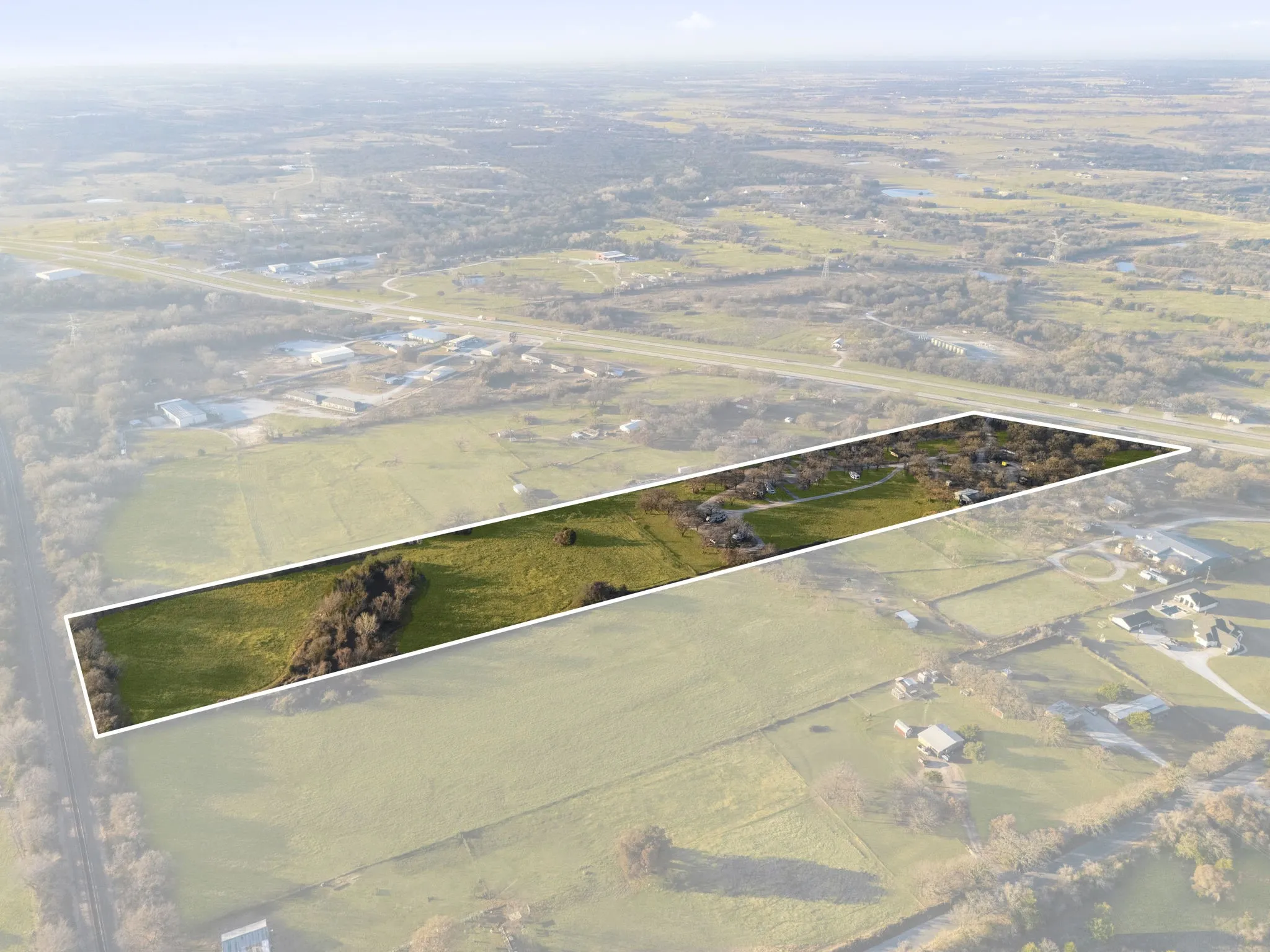 Expansive land parcel featuring a rectangular shape, natural green acreage, and a treed border