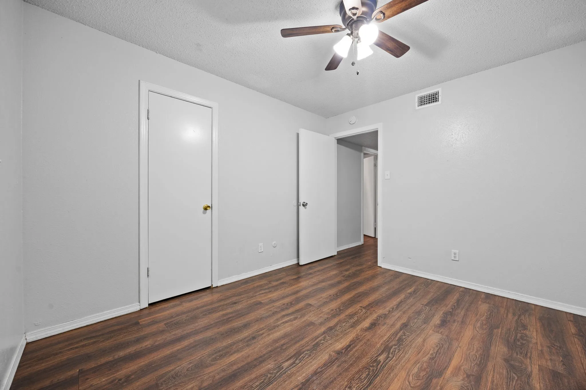 Room with wood-finish flooring, a ceiling fan with light fixture, and light gray painted walls