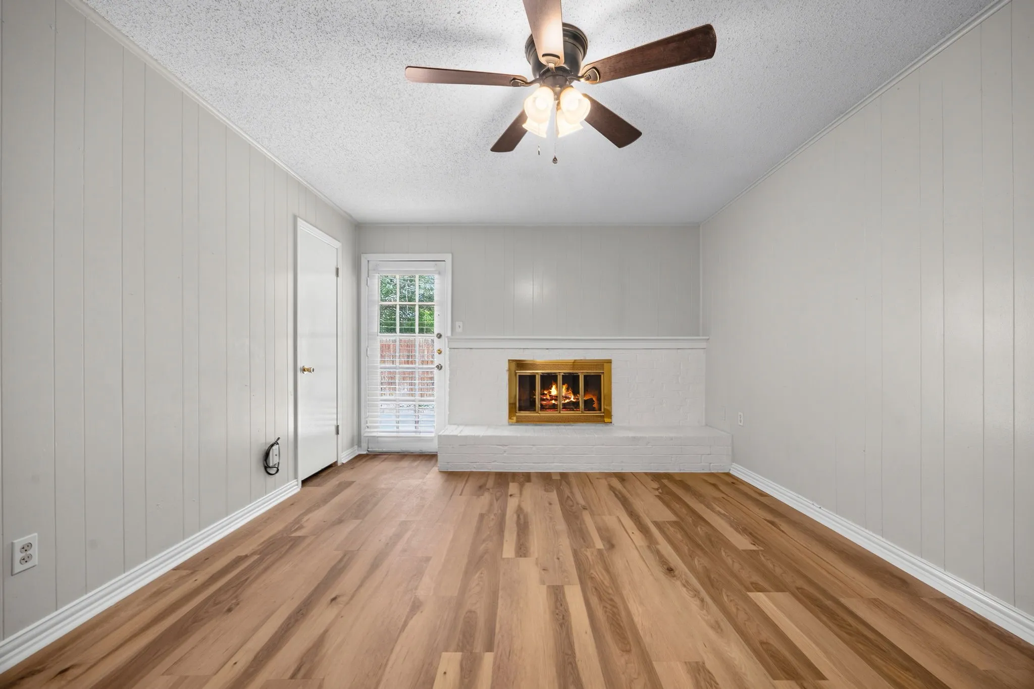 Living space with a white painted brick fireplace, gold-toned firebox, and a hearth