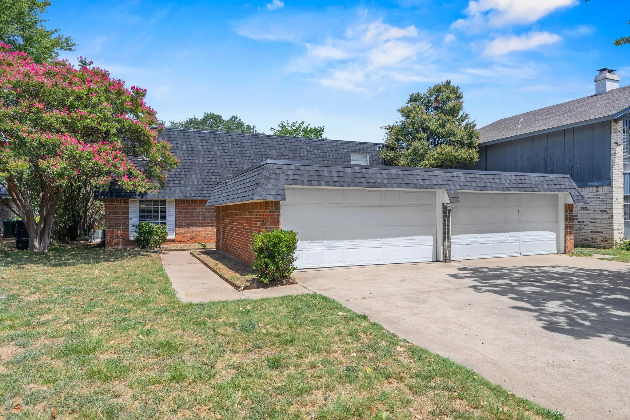 Brick facade home with a two-car attached garage, featuring a concrete driveway and sidewalk