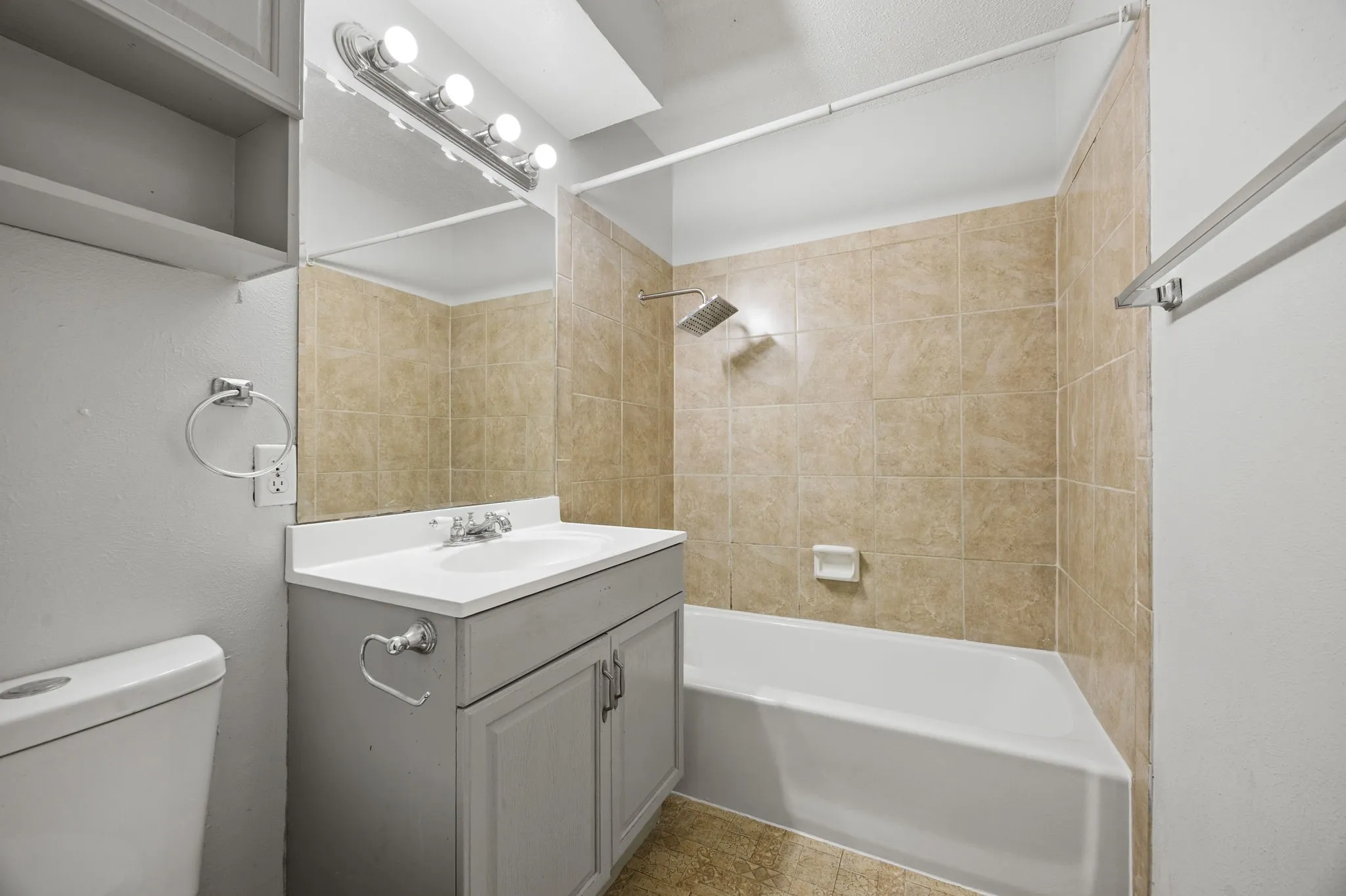 Bathroom featuring a single vanity with a white countertop and basin sink, a wall-mounted mirror, and overhead strip lighting
