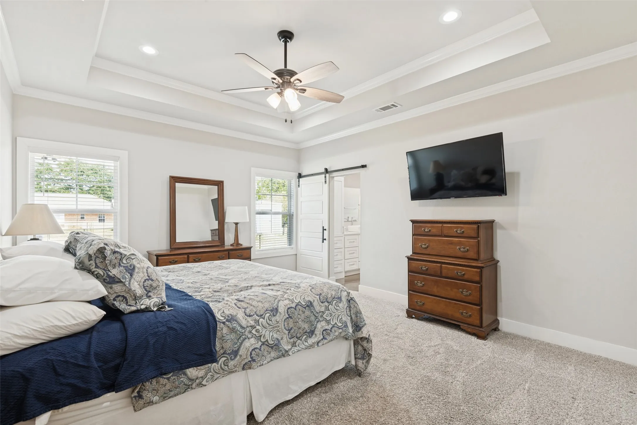 Recessed lighting, tray ceiling, ceiling fan, white trim windows, and barn door entry