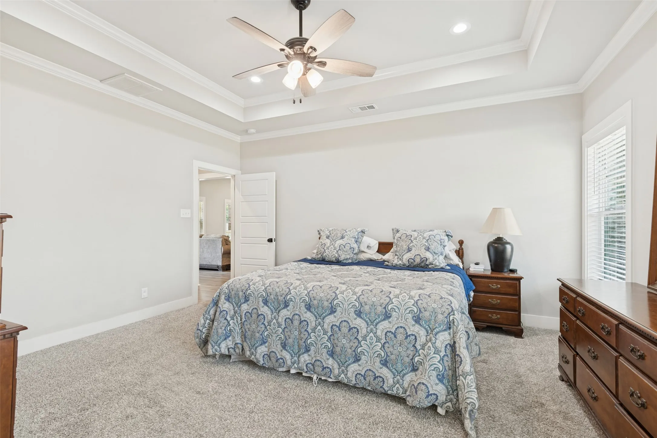 Recessed lighting, ceiling fan with light fixture, tray ceiling, carpet flooring, and white window blinds