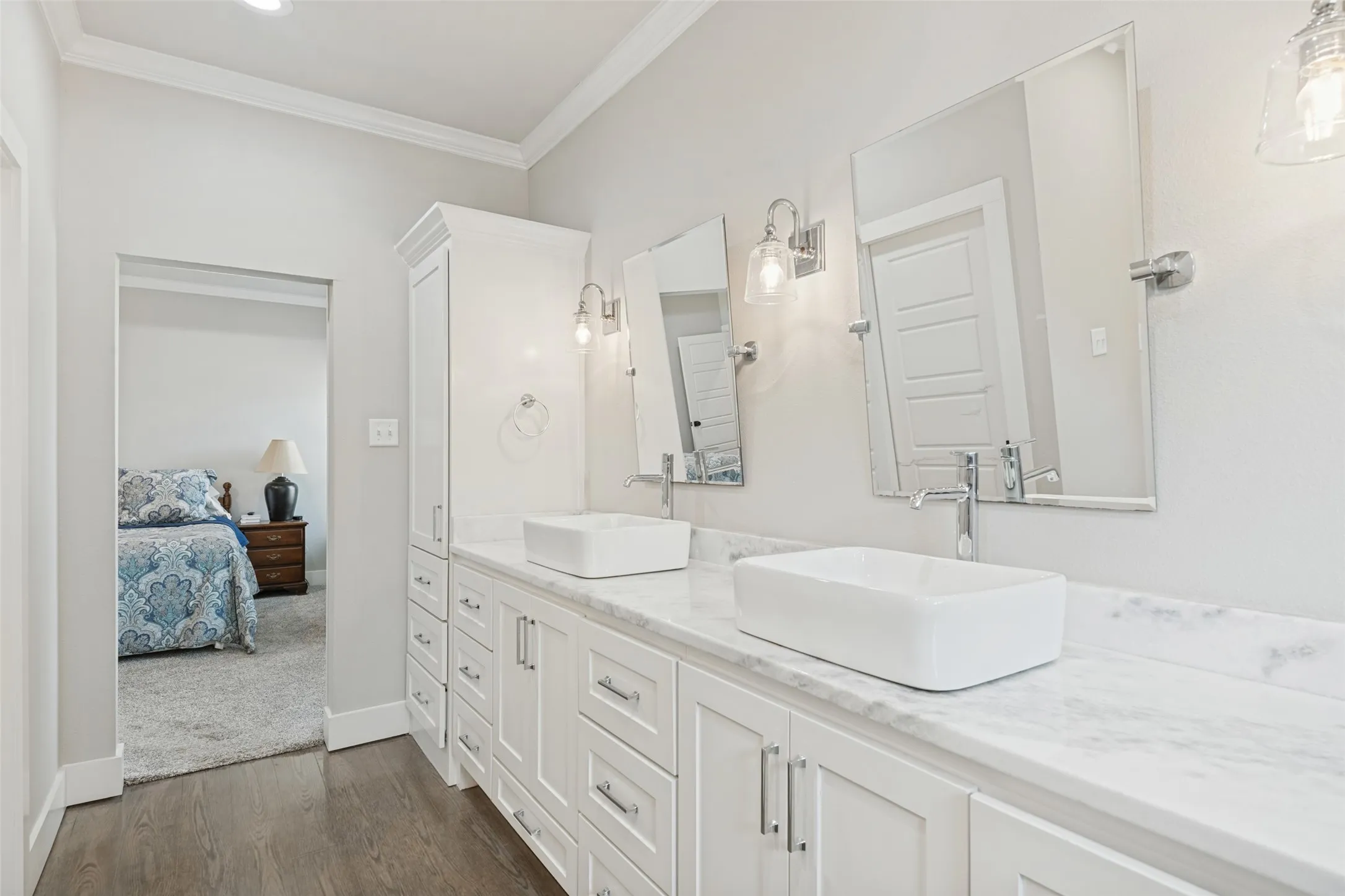Dual vessel sinks set on a stone countertop with white shaker cabinetry, individual wall-mounted mirrors, and chrome fixtures