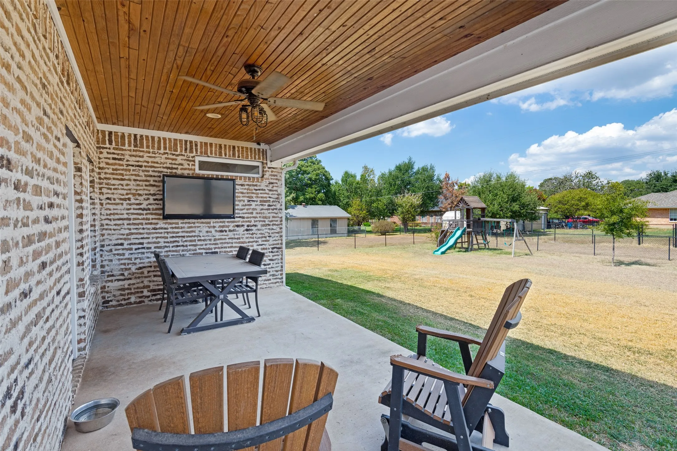 Covered patio with a wood-finish plank ceiling and a ceiling fan
