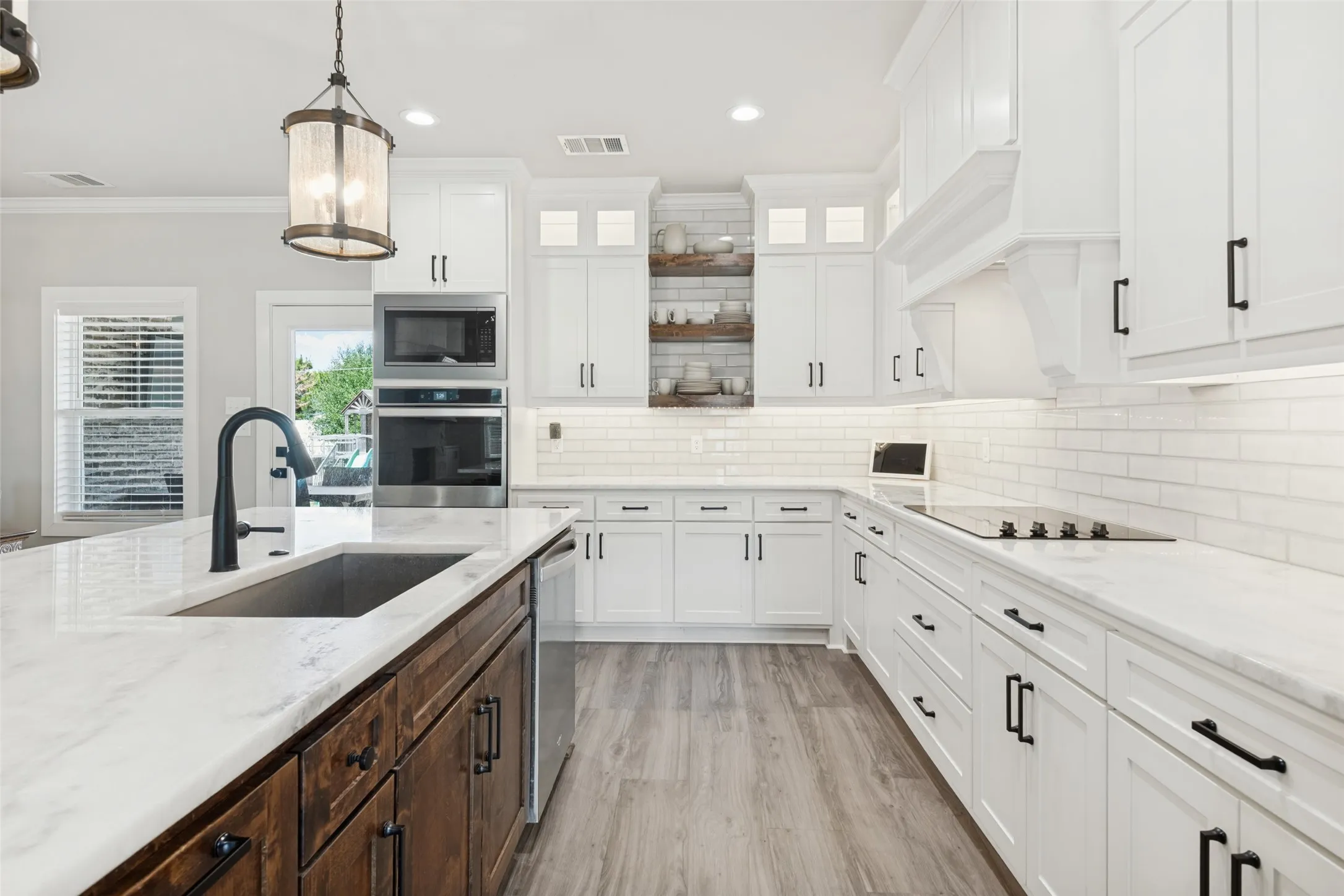 Kitchen featuring white cabinetry, subway tile backsplash, white countertops, built-in stainless steel appliances, and a wood-finish flooring