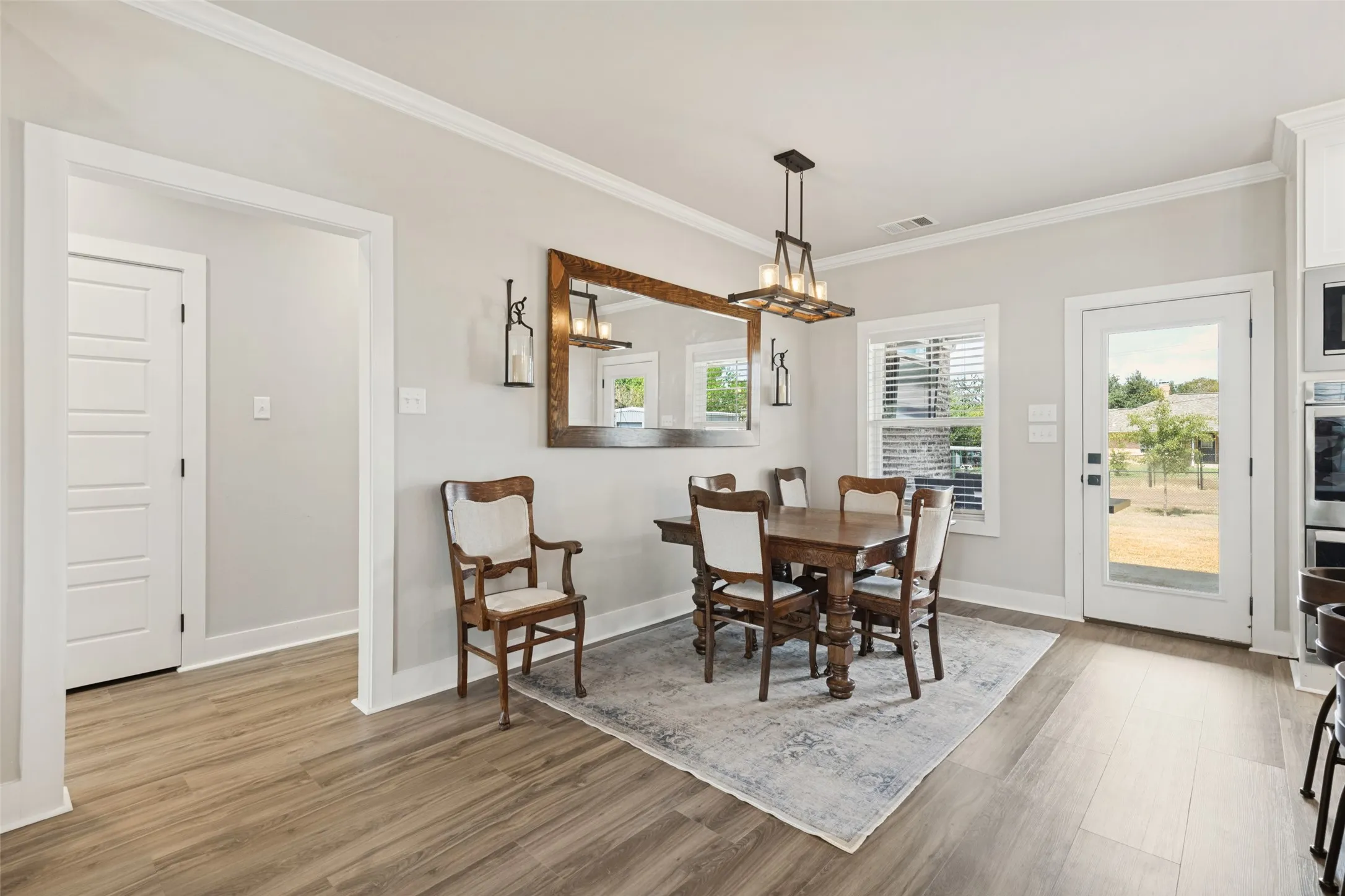 Wood-finish flooring, crown molding, white paneled interior doors, and a glass-paneled exterior door