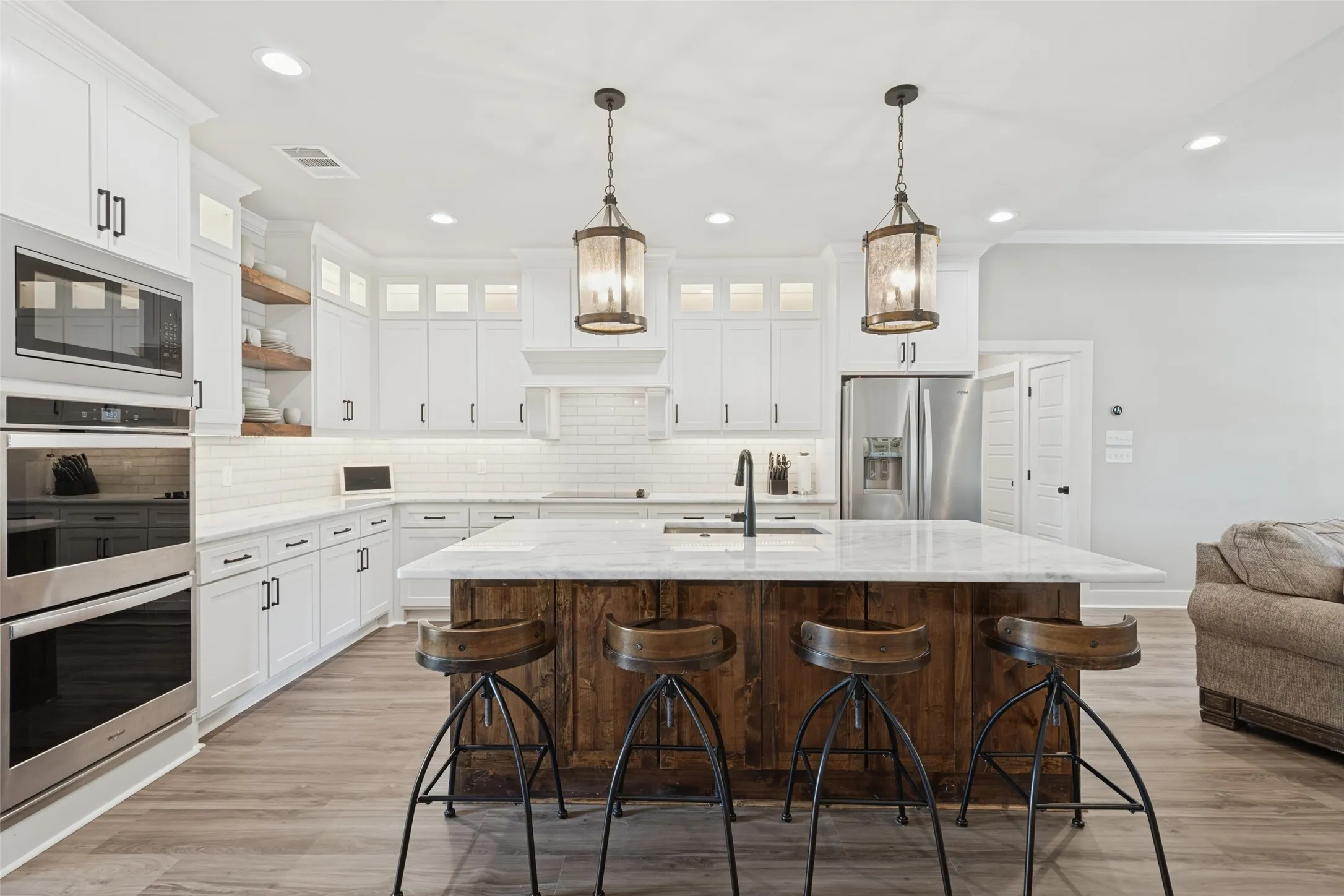 Kitchen featuring a wood-finish island, white cabinetry, stainless steel appliances, and pendant lighting