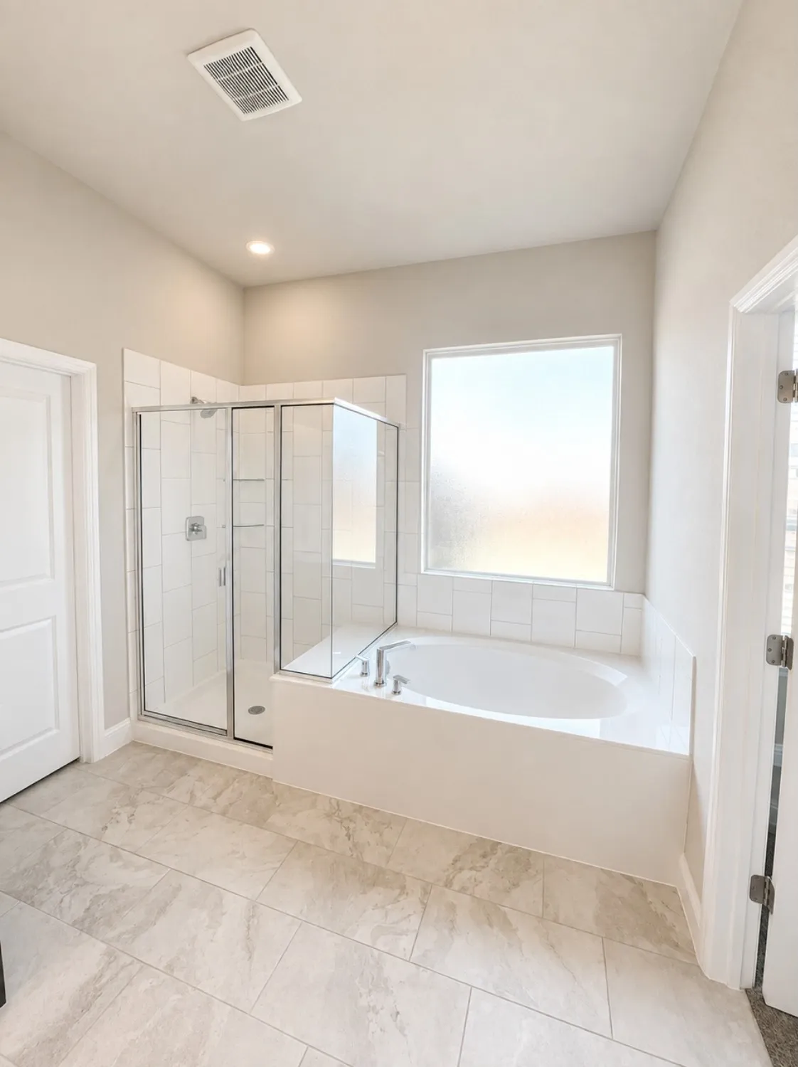 Bathroom featuring a built-in soaking tub, a framed glass shower enclosure, and light-toned tile flooring
