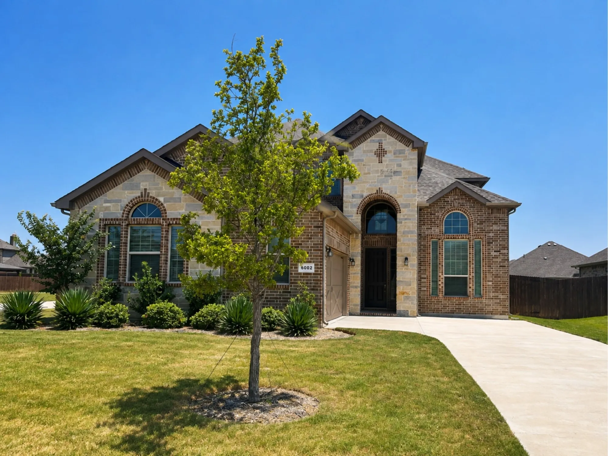 Brick and stone facade residence featuring a prominent arched entryway and complementary arched windows