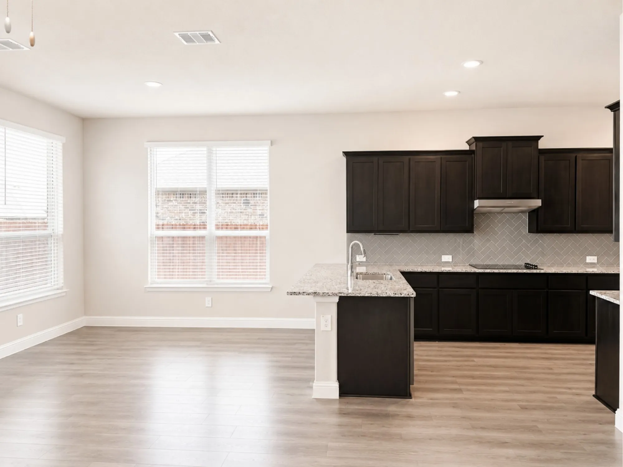 Kitchen featuring dark wood cabinetry, light granite countertops, stainless steel appliances, and a gray subway tile backsplash