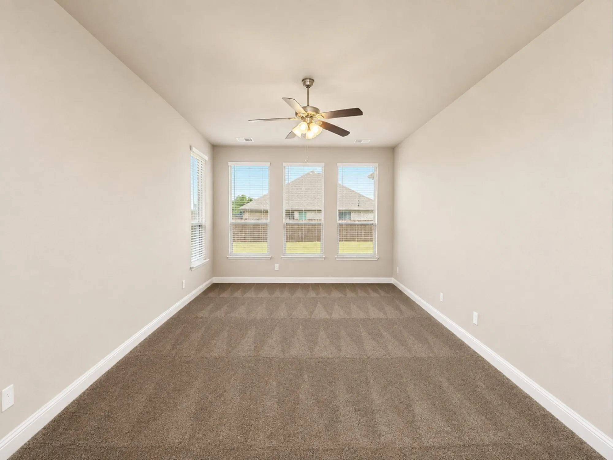 Spacious room featuring vaulted ceilings, a ceiling fan with integrated lighting, and three tall windows with blinds