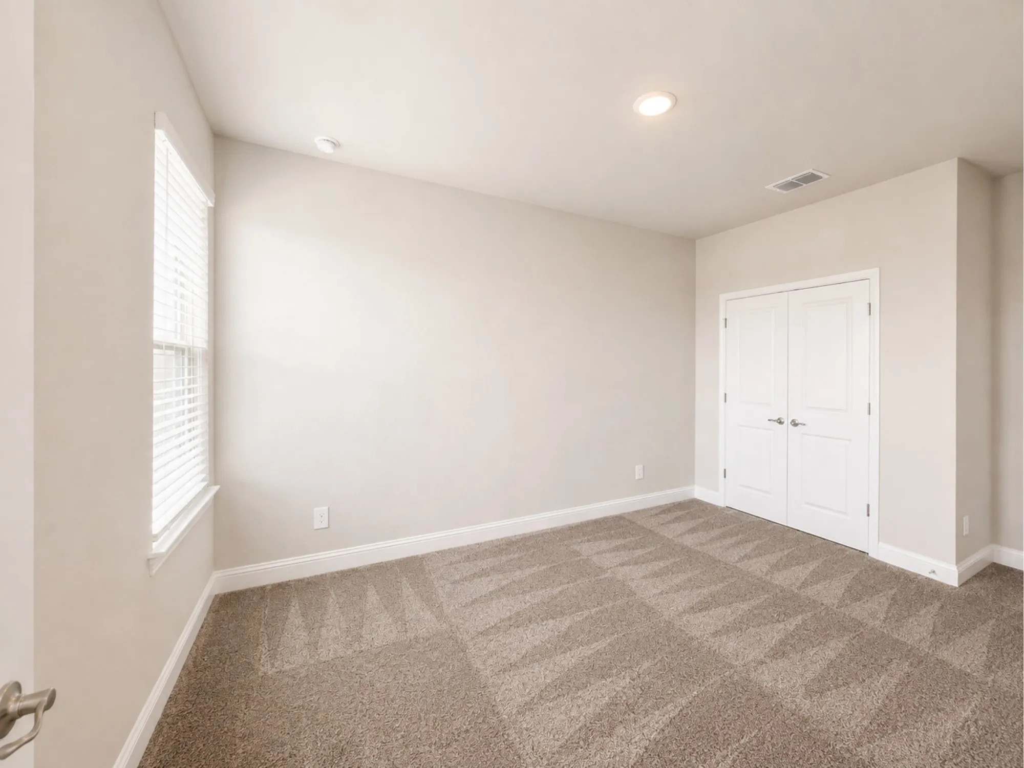 Bright bedroom featuring neutral wall finishes, recessed ceiling lighting, a large window with natural light, carpeting in neutral tones, and a double-door closet for ample storage