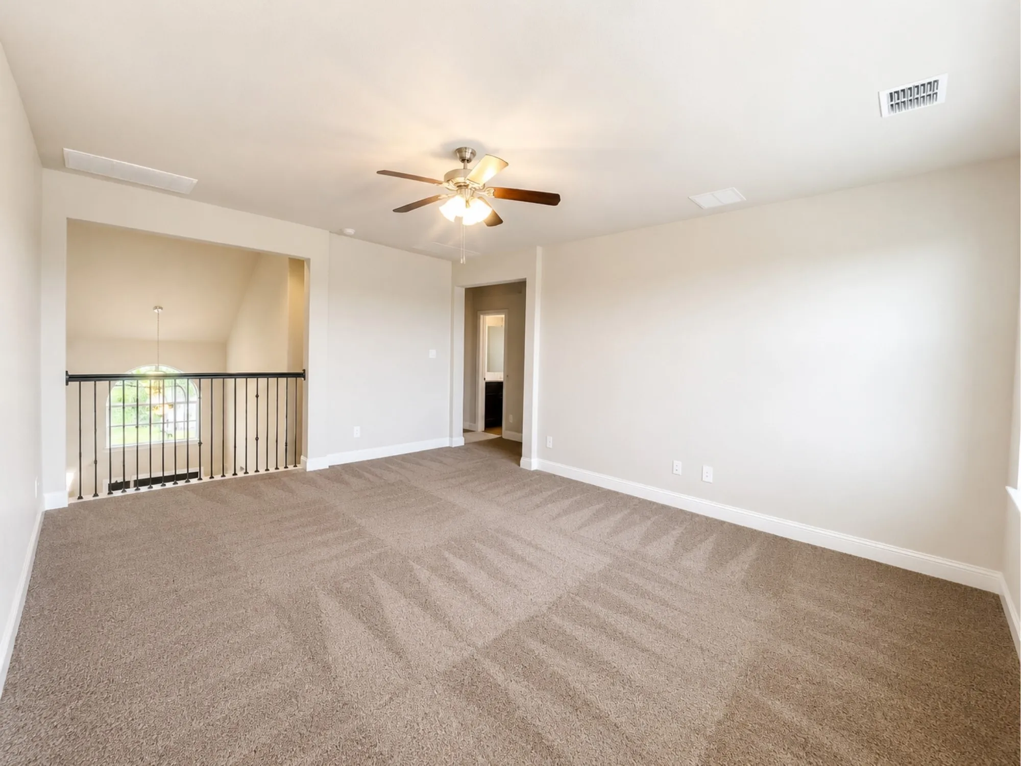 Spacious carpeted loft area featuring a ceiling fan, a railing overlooking a lower level, and ample wall space