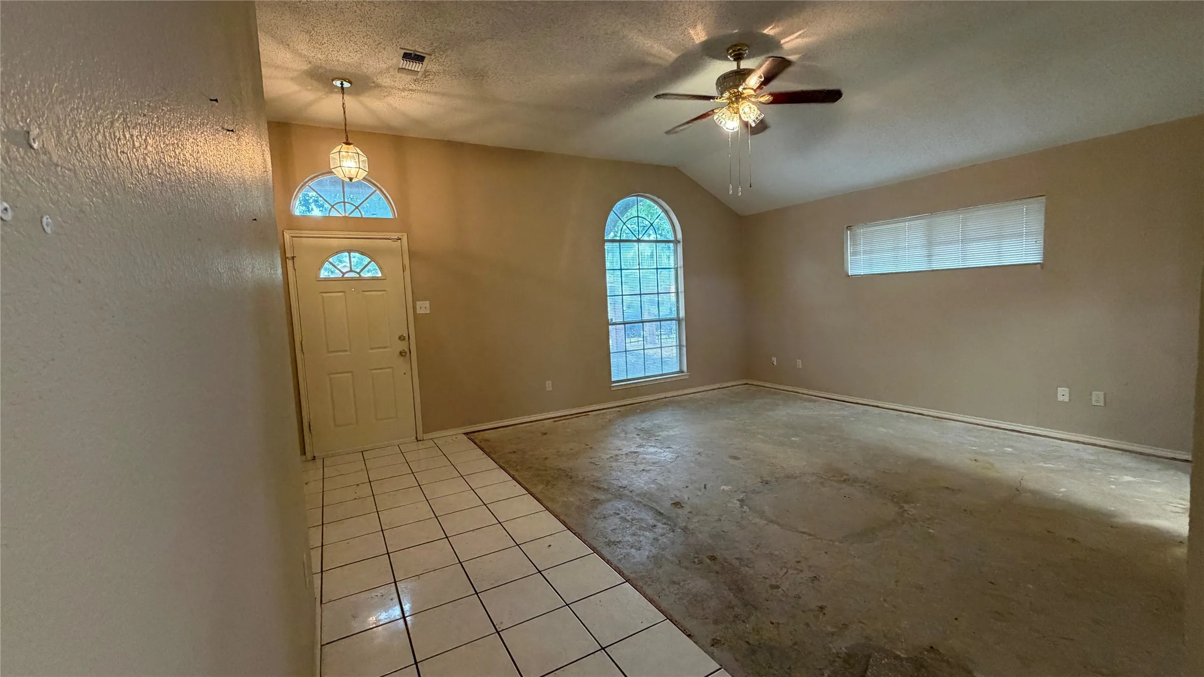 Arched window and transom above the entry, vaulted ceiling, and ceiling fan