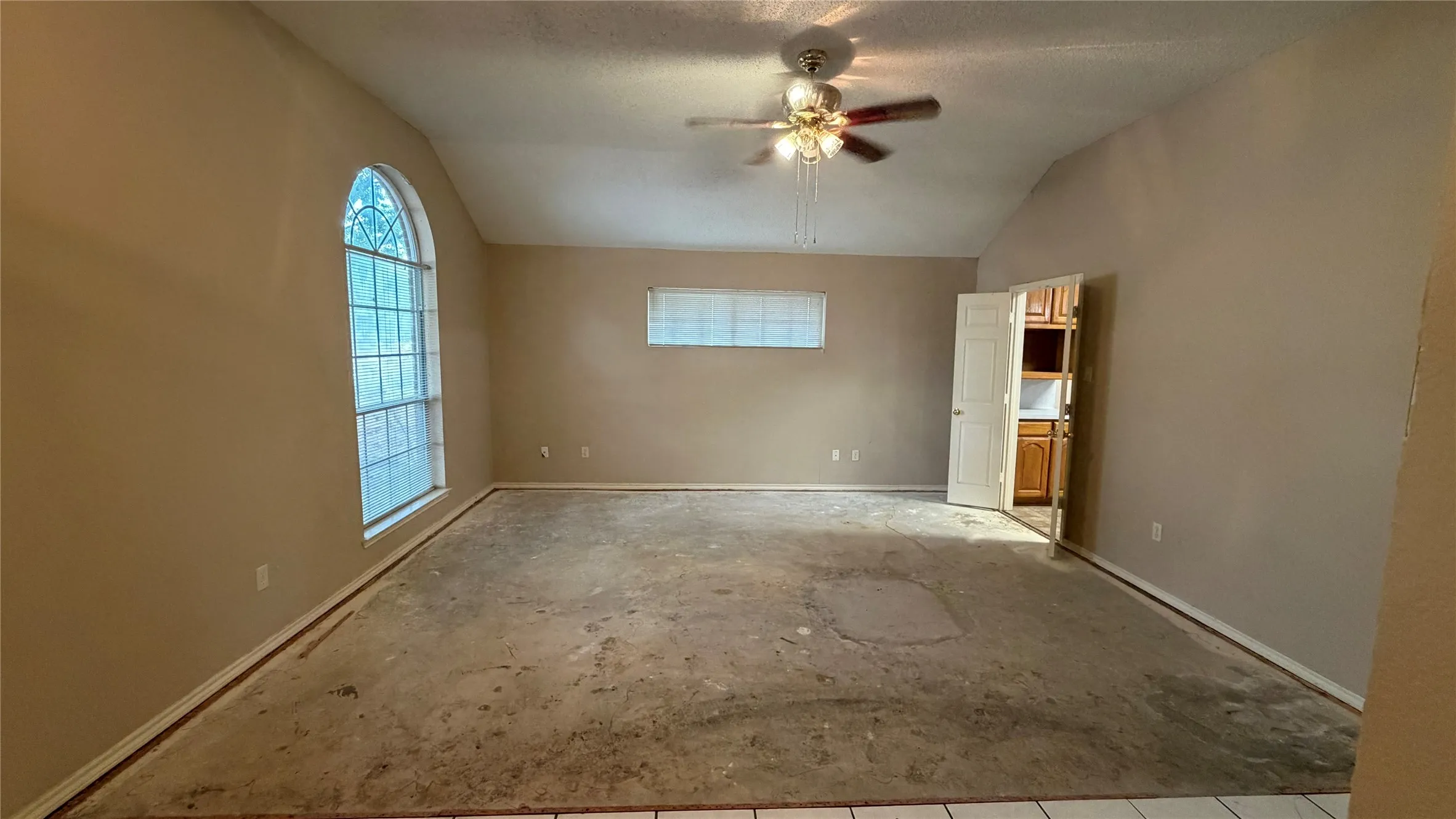 Vaulted ceiling with ceiling fan, arched window, and additional rectangular window