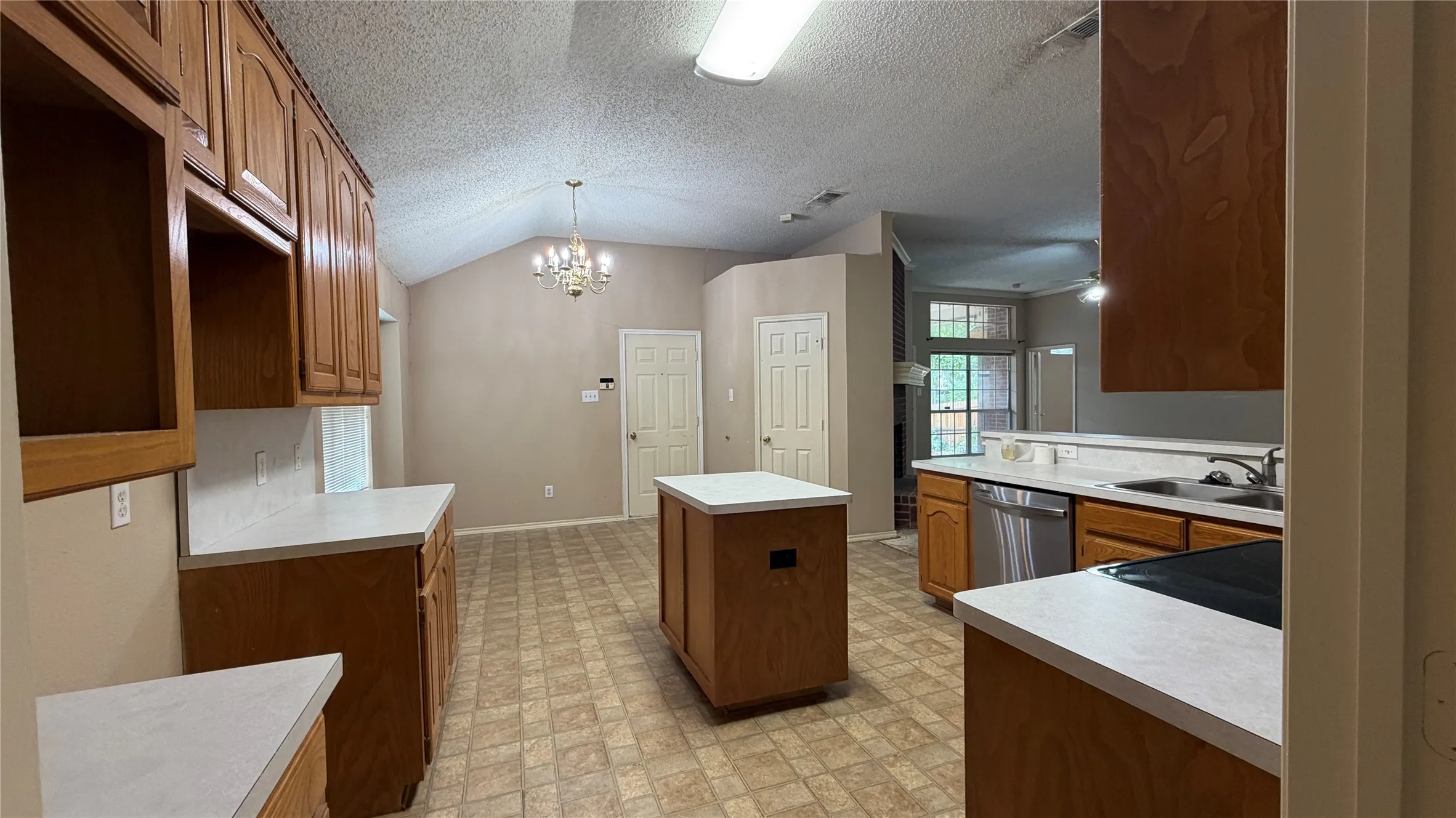Kitchen featuring wood cabinetry, white countertops, stainless steel appliances, a center island, and vaulted ceilings