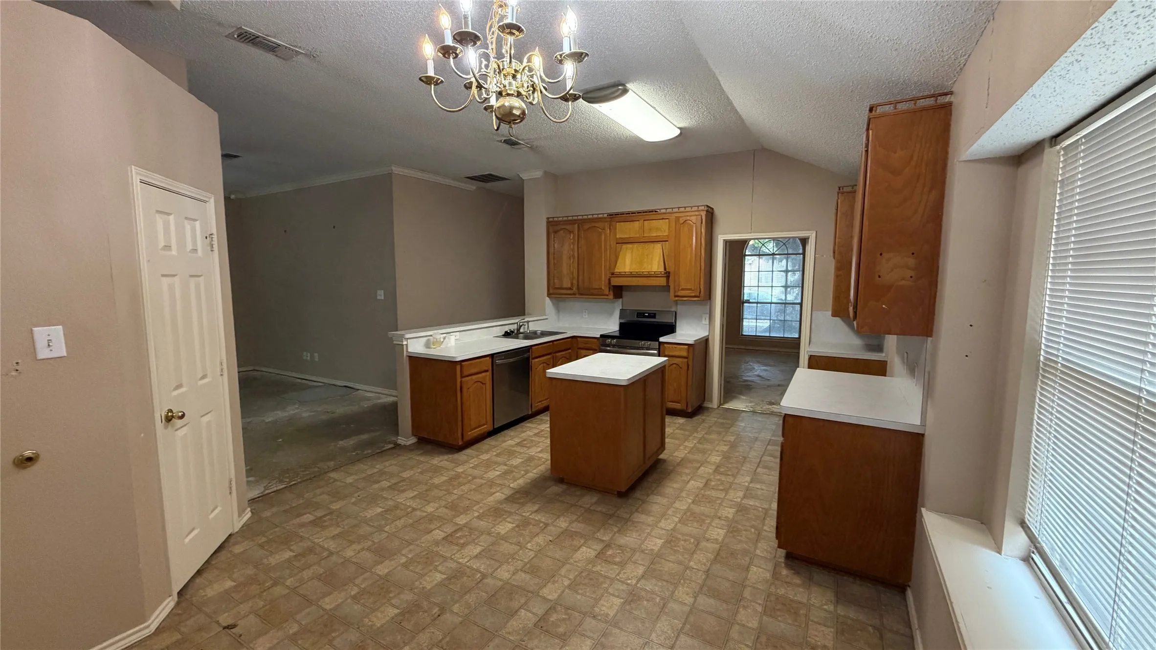 Kitchen with wood-finish cabinetry, white countertops, a central island, and a stainless steel sink
