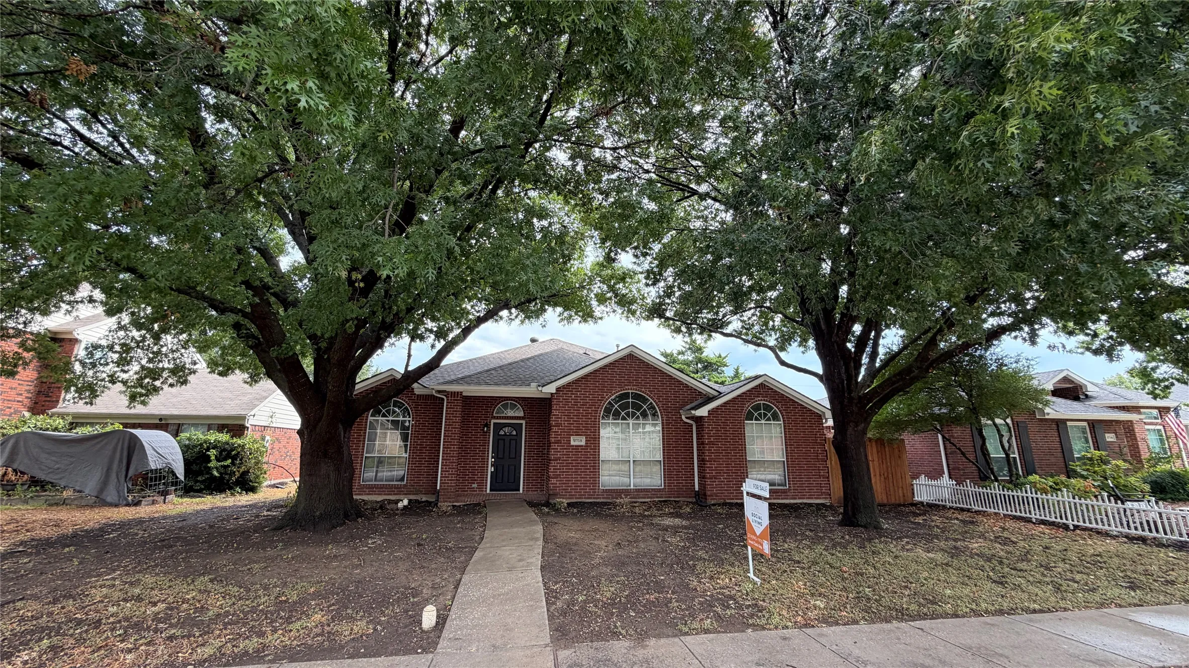 Brick exterior with arched window details, a dark front door, and a concrete pathway