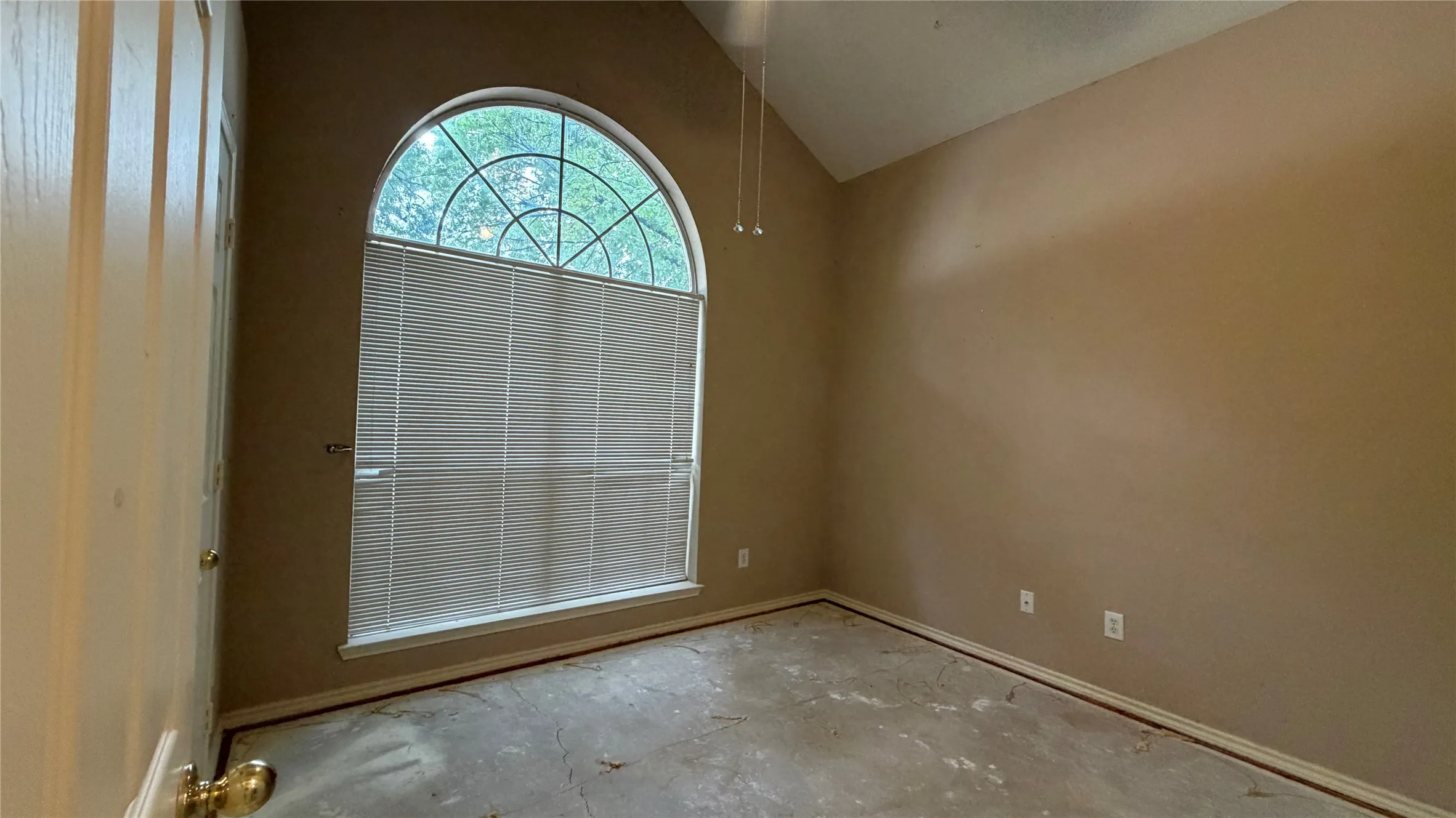 Arched window with sunburst muntins, vaulted ceiling, and ceiling fan