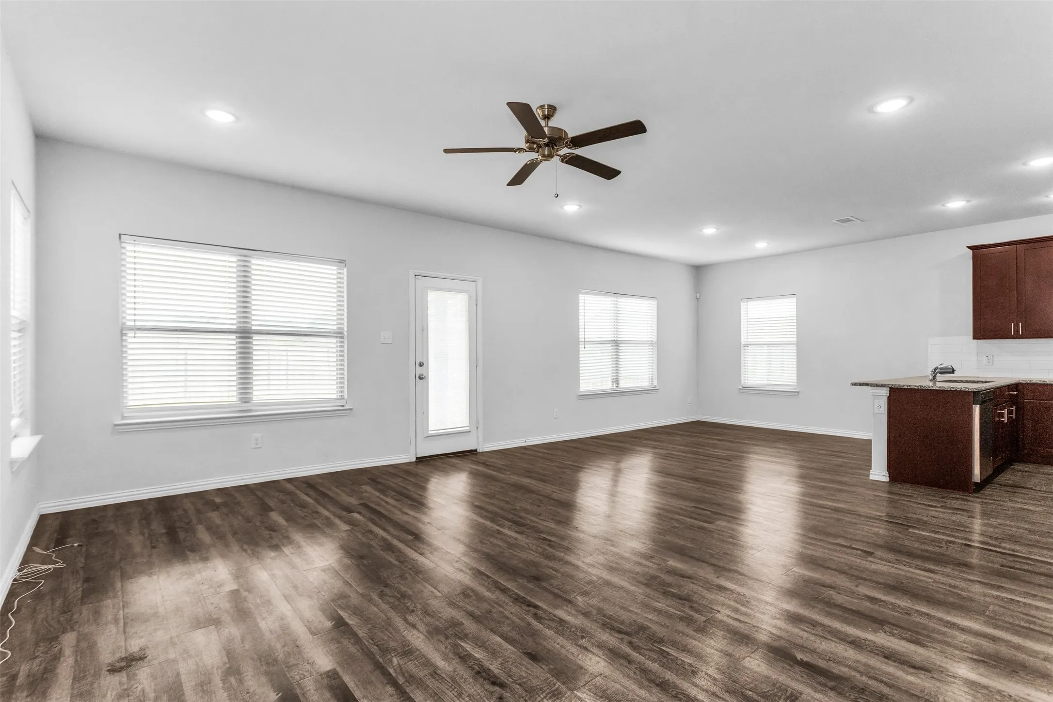 Spacious living area featuring wood-finish flooring, recessed lighting, and a ceiling fan