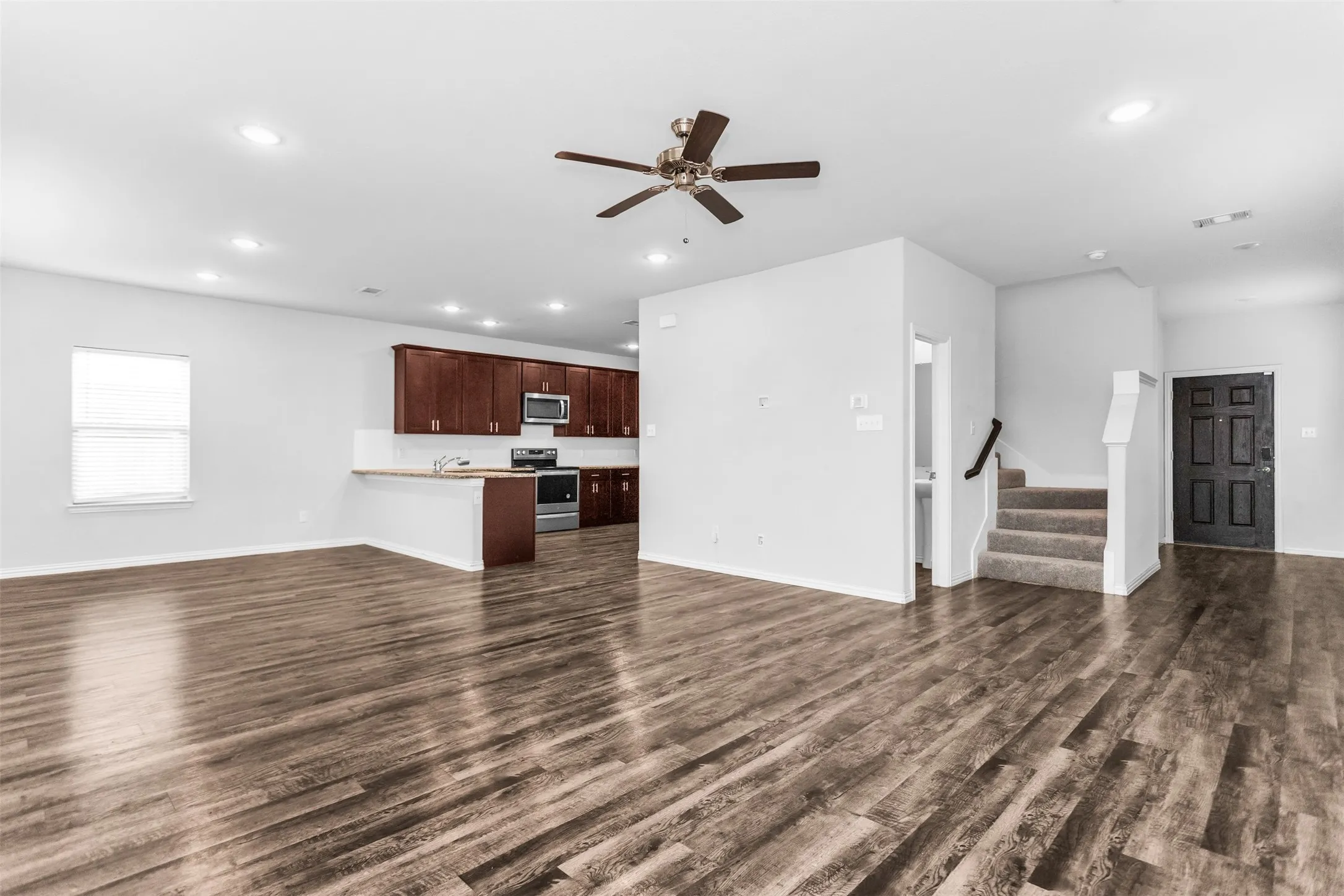 Open-concept living area featuring wood-finish flooring, recessed lighting, and a ceiling fan