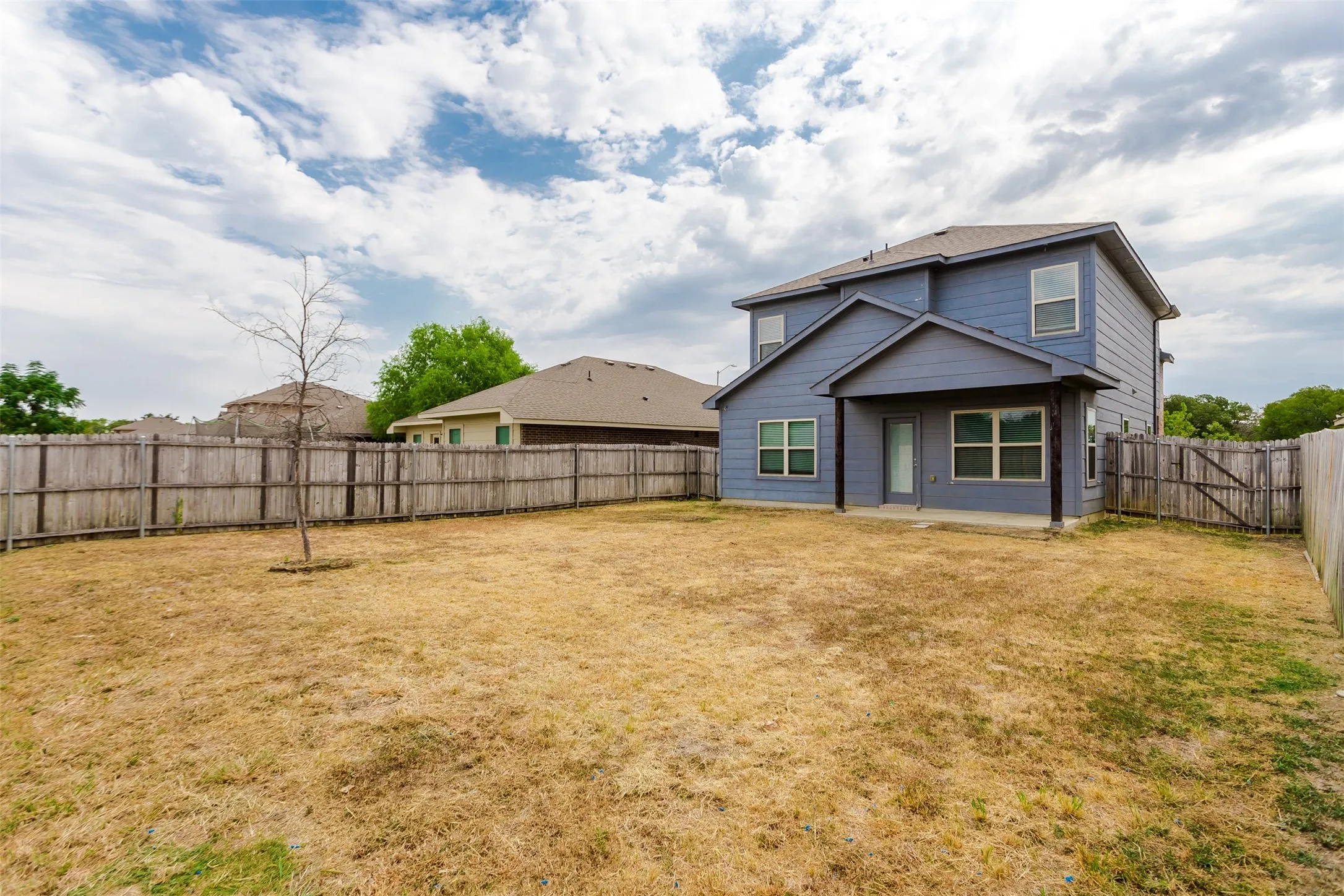 Two-story residence with a covered patio, enclosed by a wood privacy fence