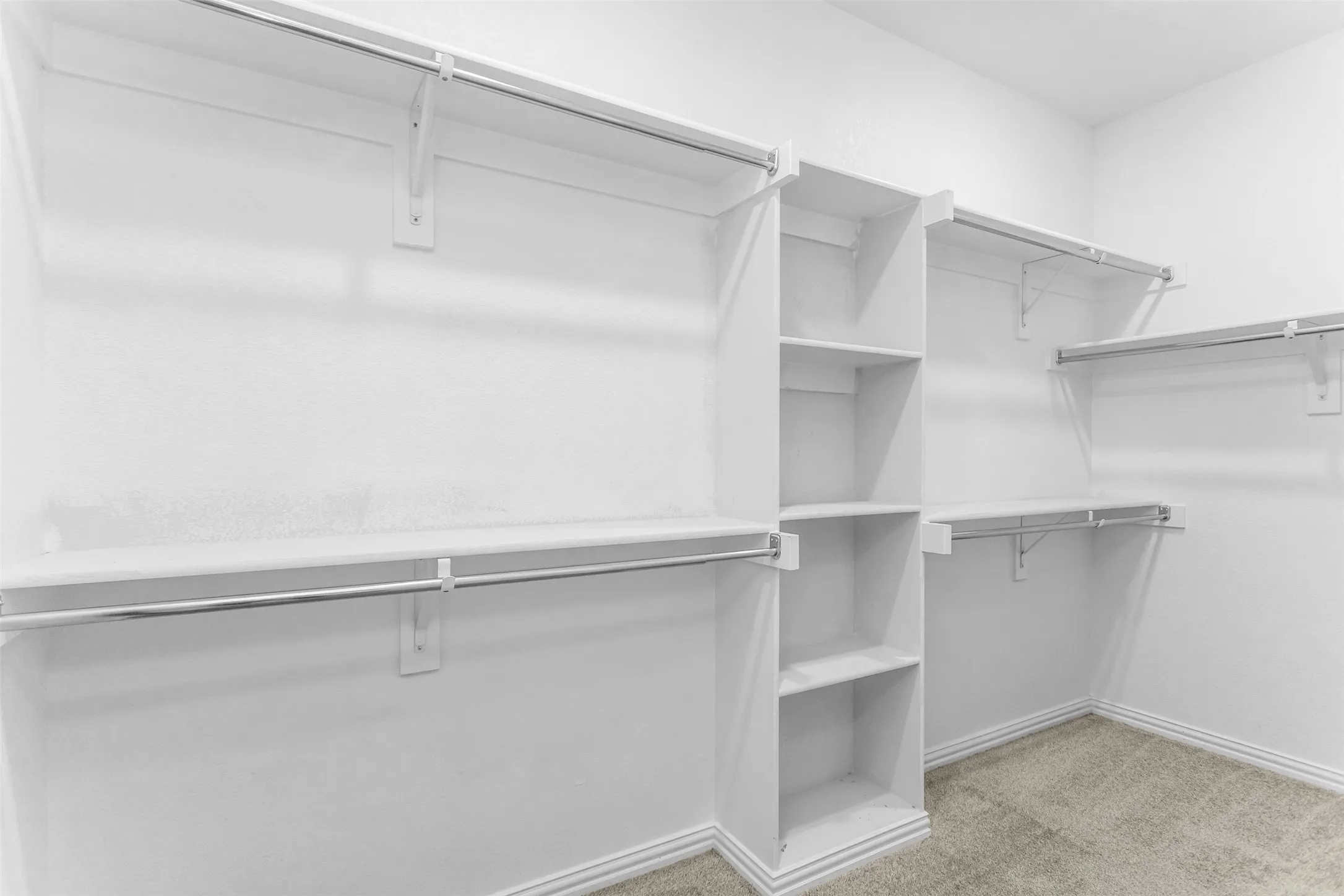 Custom closet system featuring multiple hanging rods, built-in shelving, and carpet flooring