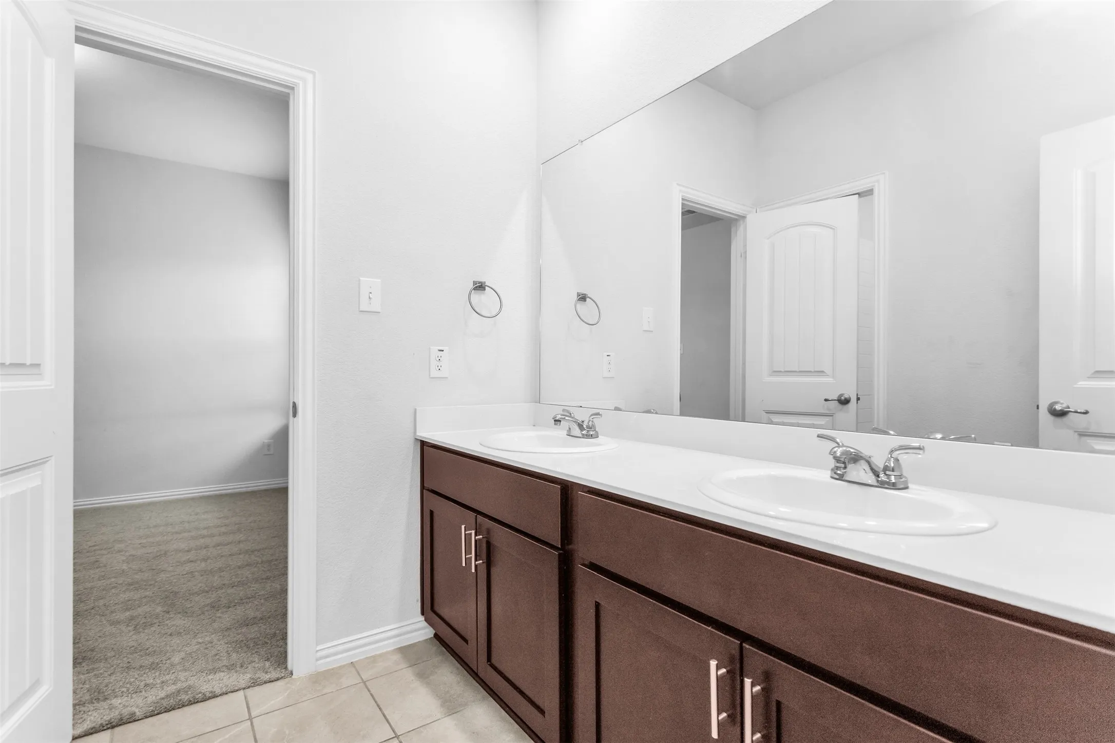 Dual vanity with white countertop, recessed sinks, and wood-finish cabinetry