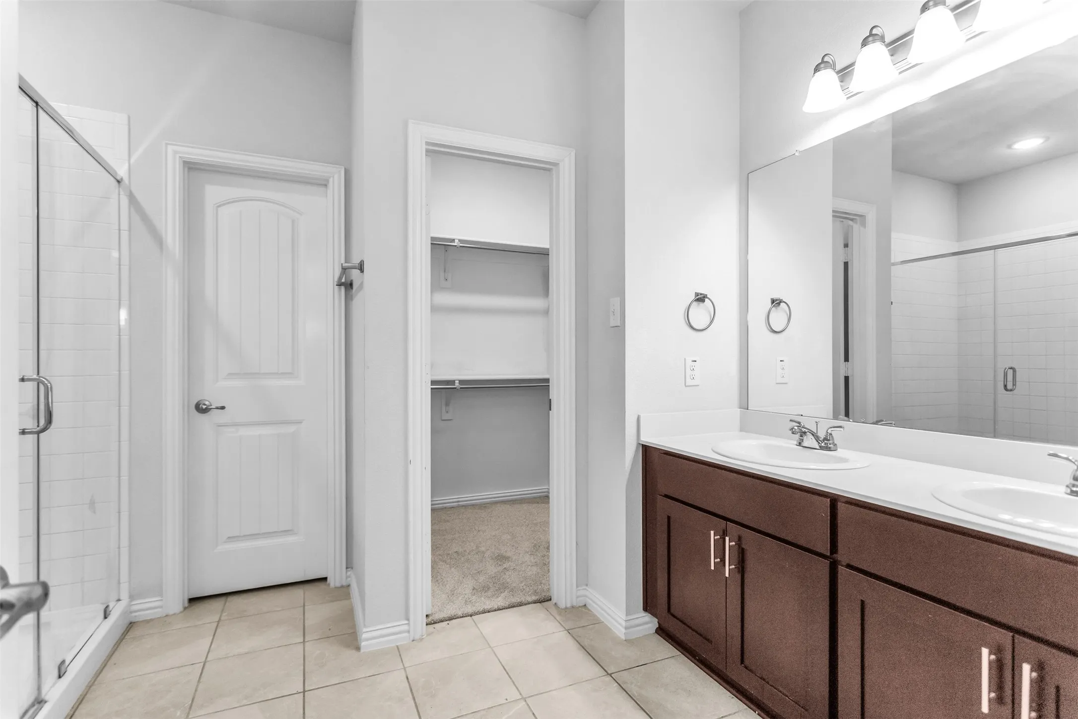 Dual vanity with integrated sinks, wood-finish cabinetry, and a large mirror