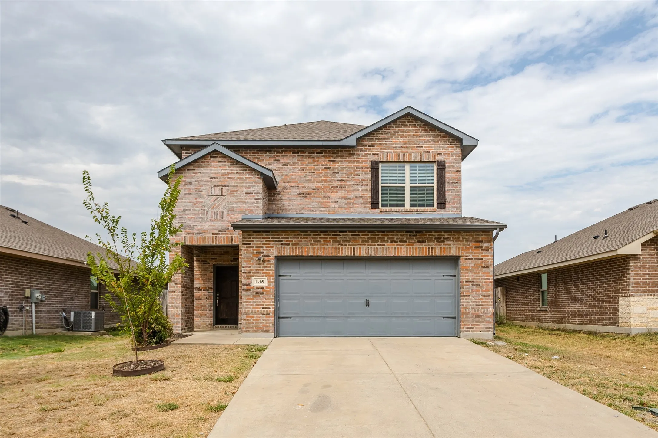 Brick facade with stone accents, covered entry, and attached garage
