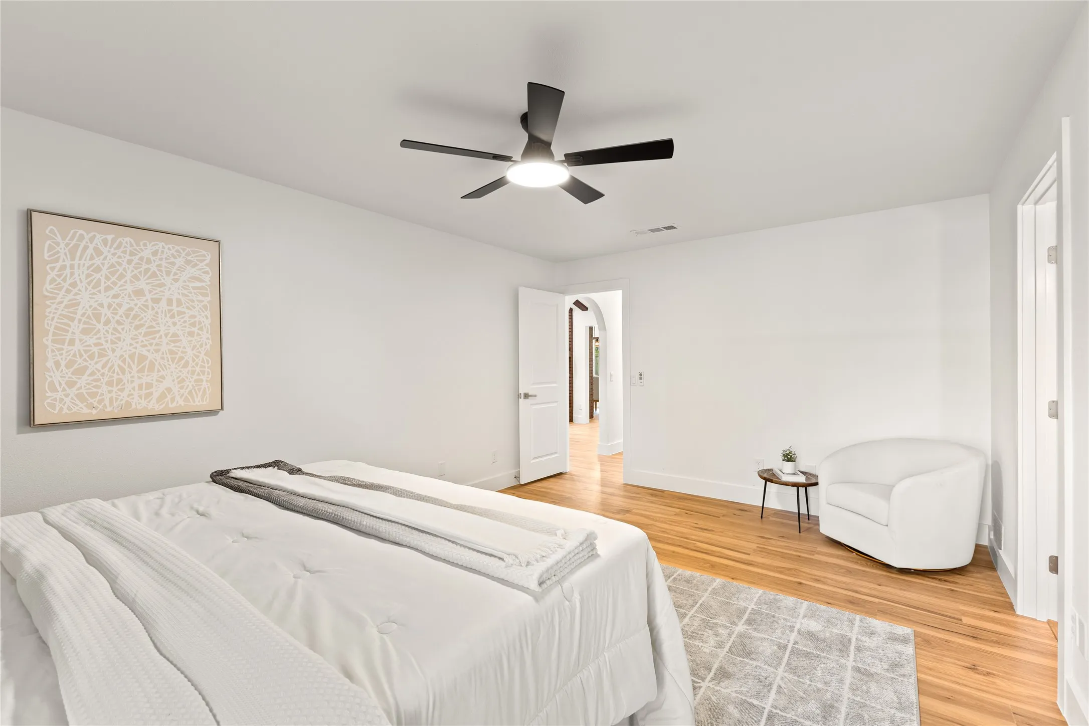 Hardwood flooring, white painted walls, ceiling fan with integrated lighting, and a white paneled door