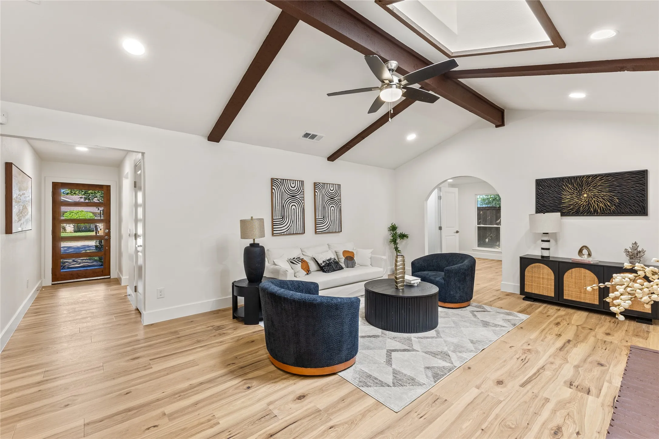 Vaulted ceiling with exposed wood beams, wood-finish flooring, recessed lighting, and an arched doorway