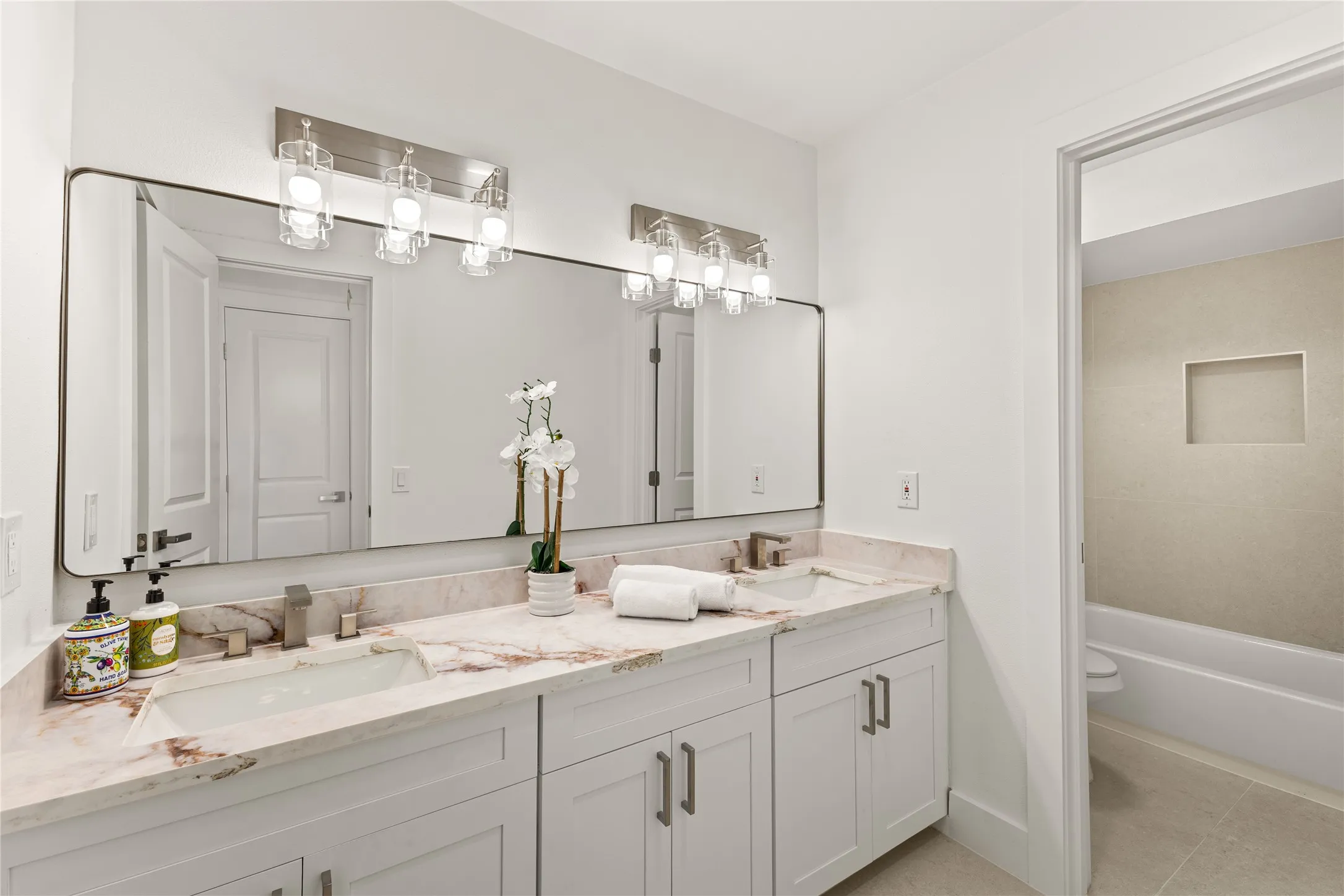 Dual vanity with stone countertop, white shaker cabinetry, rectangular undermount sinks, and brushed nickel fixtures