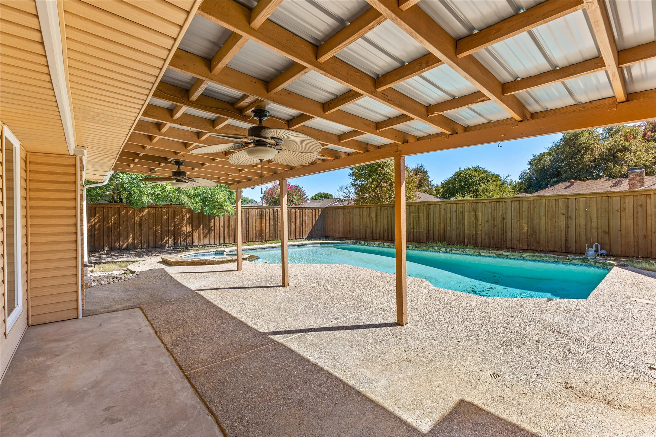 Covered patio with exposed wood framing, two ceiling fans, and a metal roof