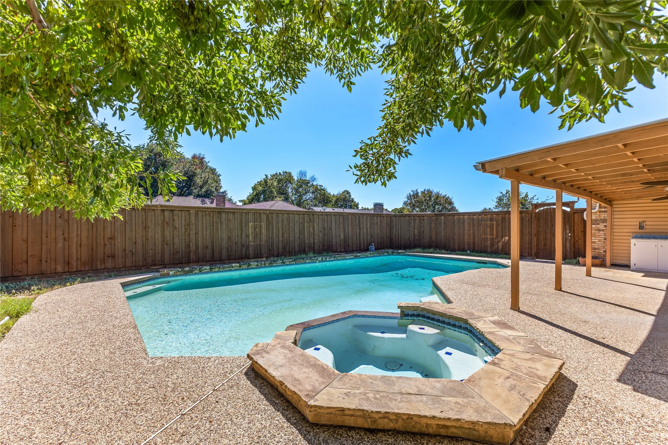 Backyard oasis featuring a swimming pool, integrated spa, and expansive aggregate concrete patio