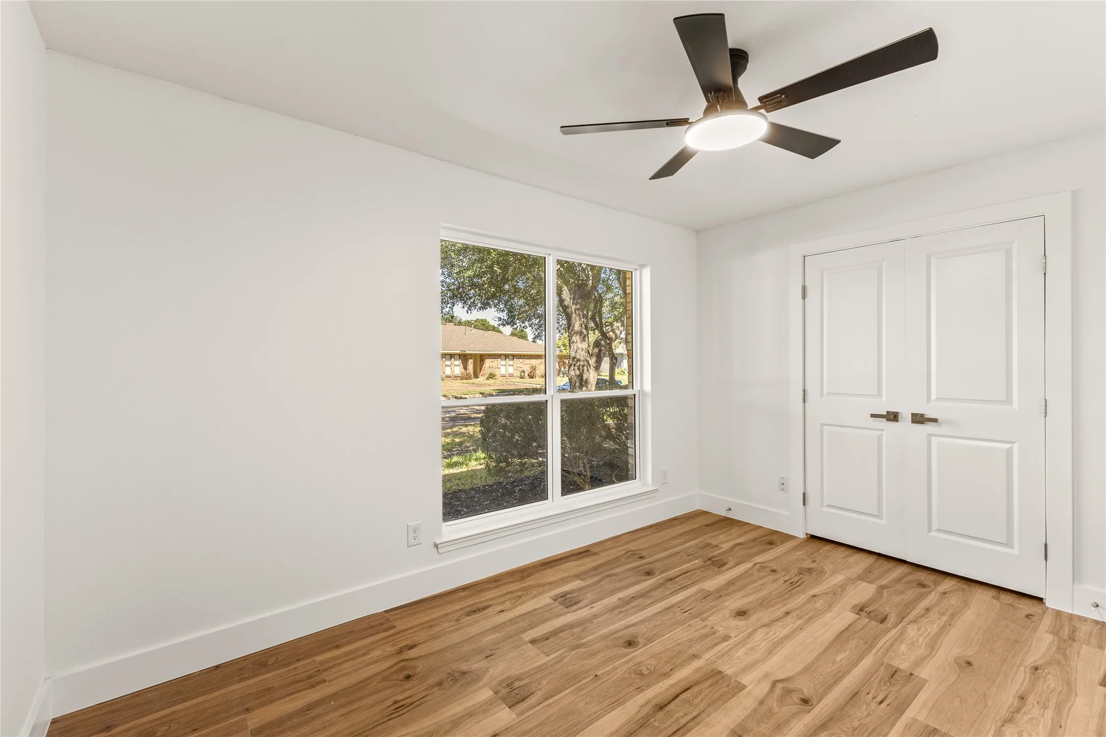 Recessed ceiling fan with integrated lighting, wood-finish flooring, and white paneled double doors