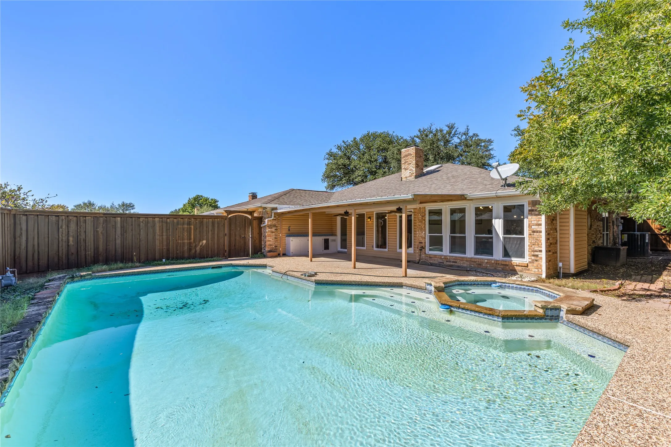 Outdoor swimming pool with integrated spa and surrounding aggregate concrete decking