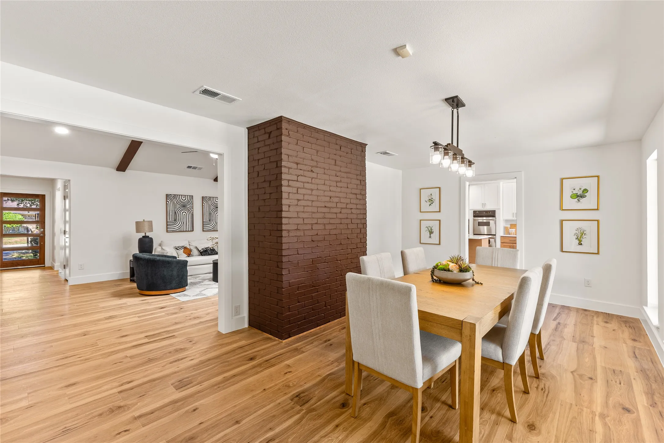 Hardwood flooring throughout, exposed brick accent wall, recessed lighting, and a modern linear chandelier