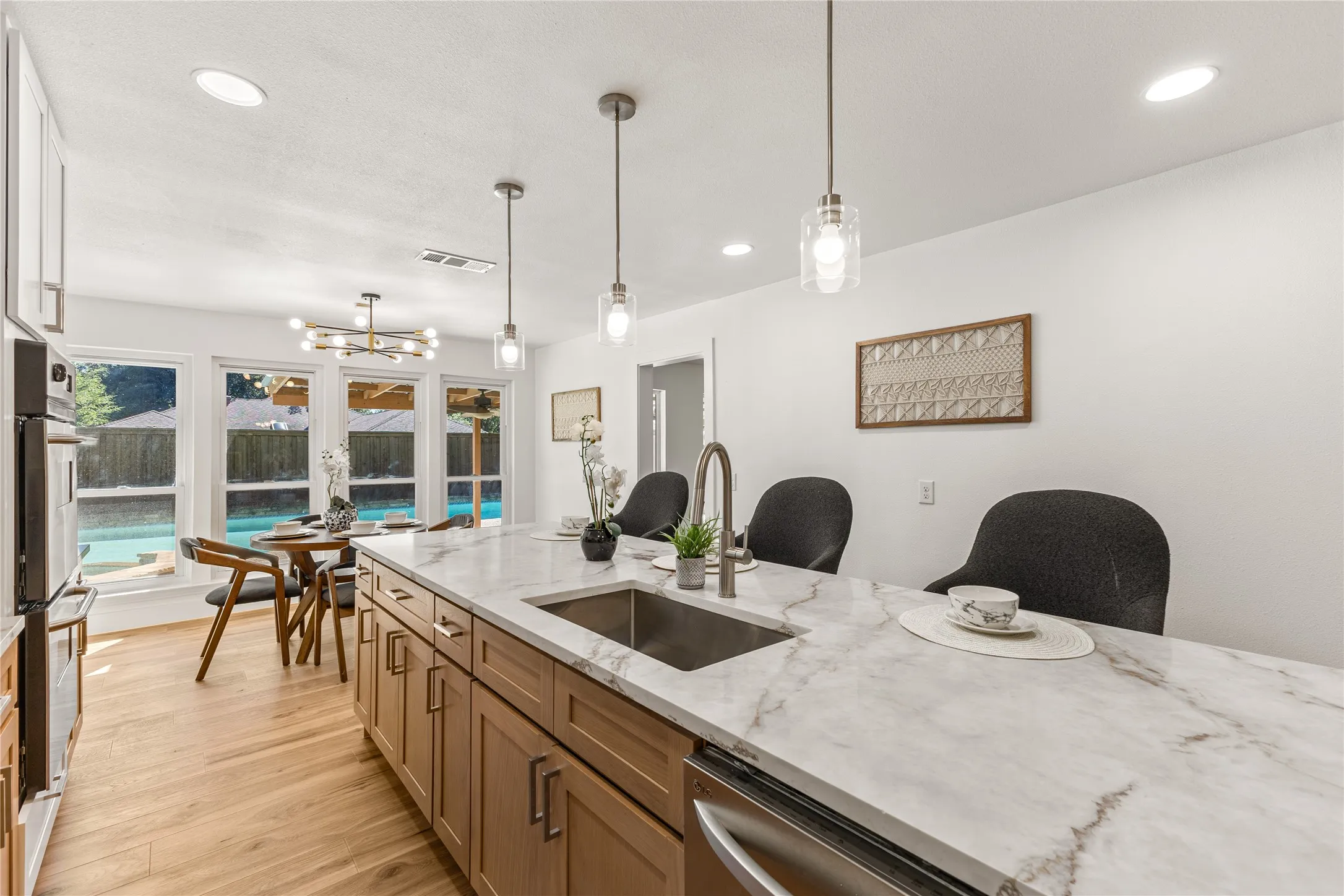 Expansive kitchen island with a stone finish countertop, integrated sink, and pendant lighting