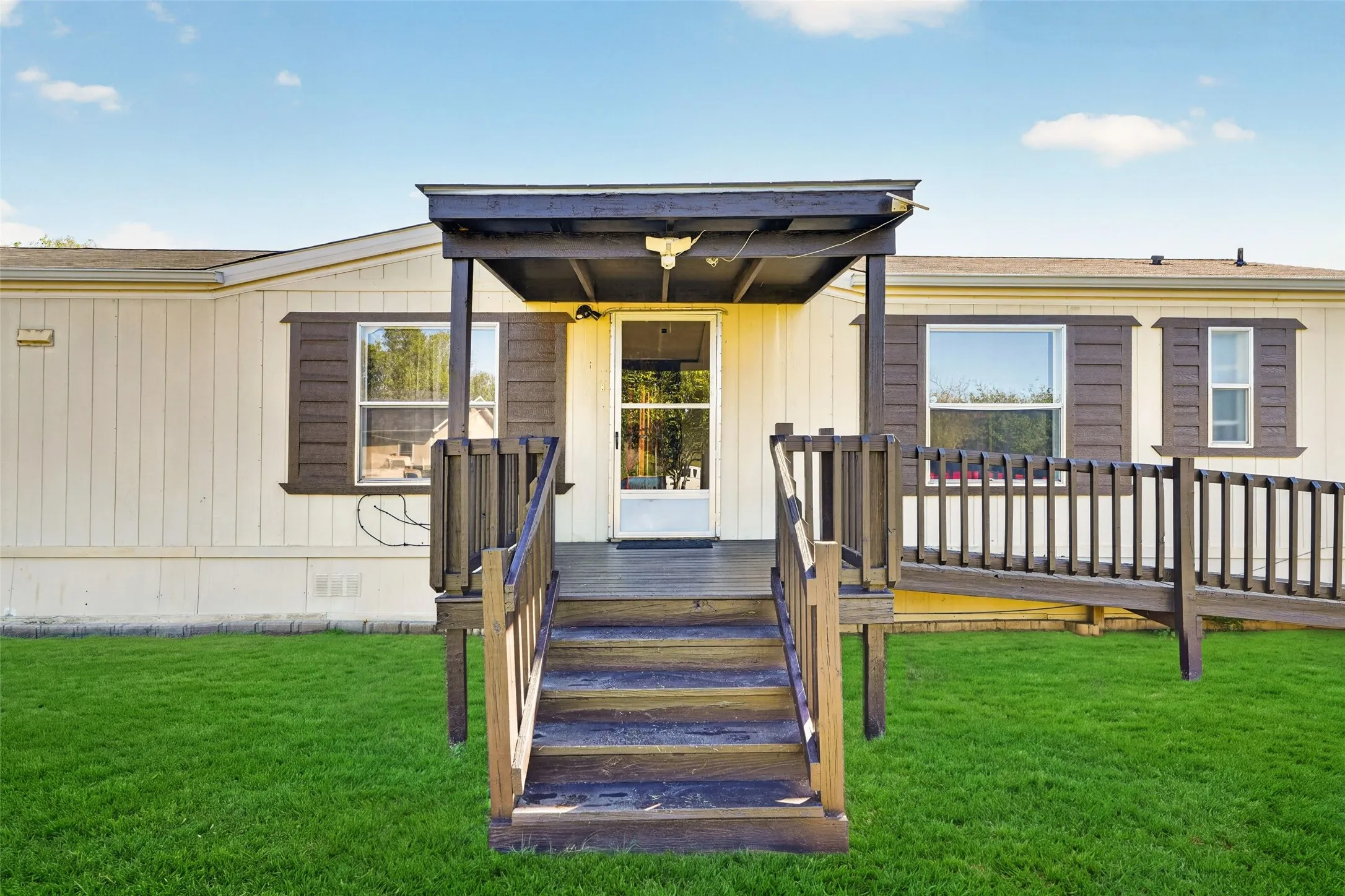 Front entry porch with steps, covered roof, and a built-in access ramp