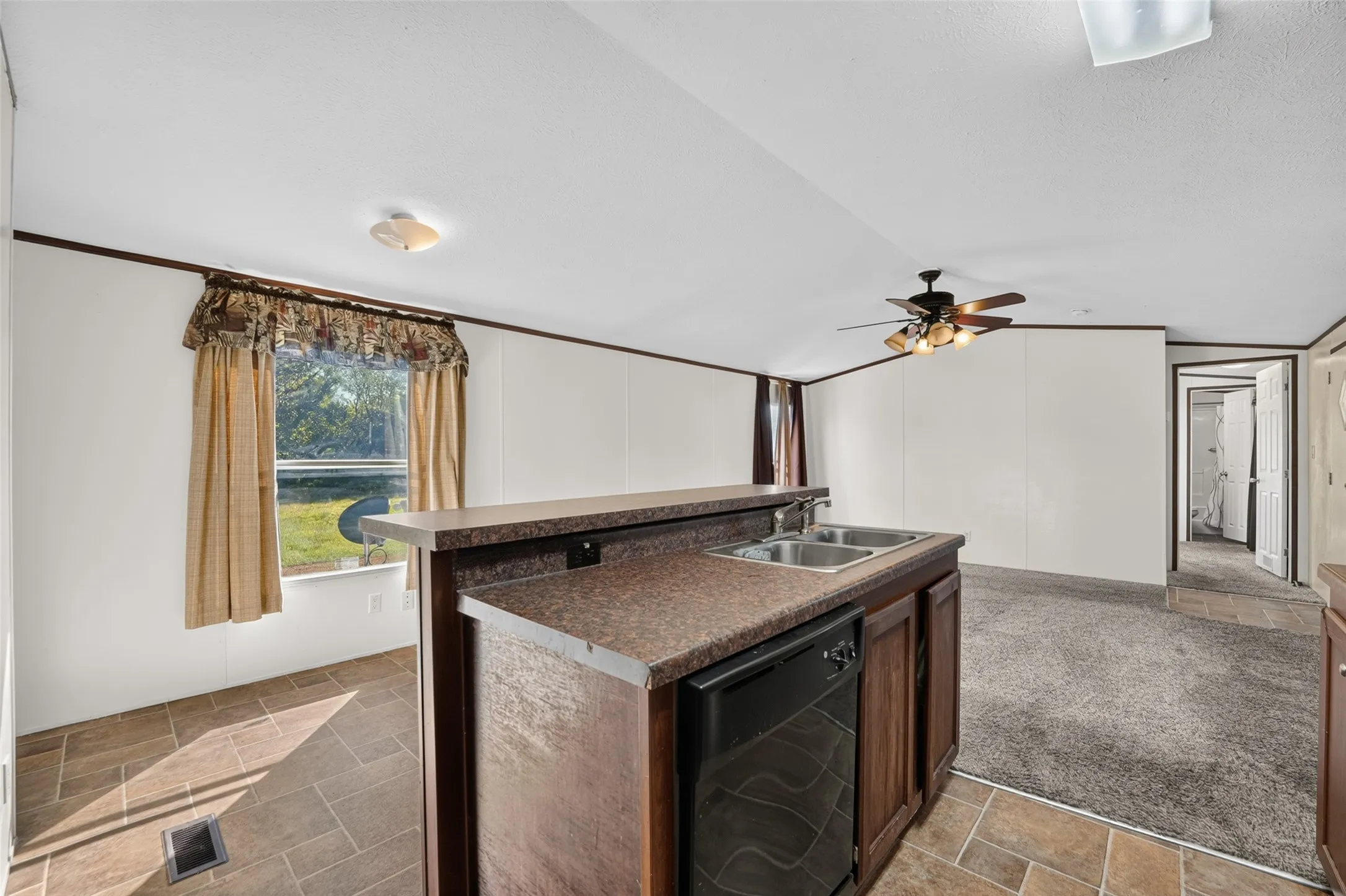 Kitchen island with dual basin sink, integrated dishwasher, and rich wood-finish cabinetry