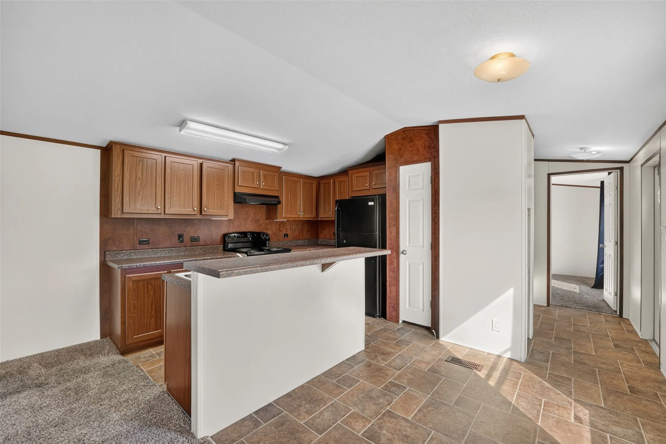 Kitchen with wood-finish cabinetry, dark countertops, and a breakfast bar