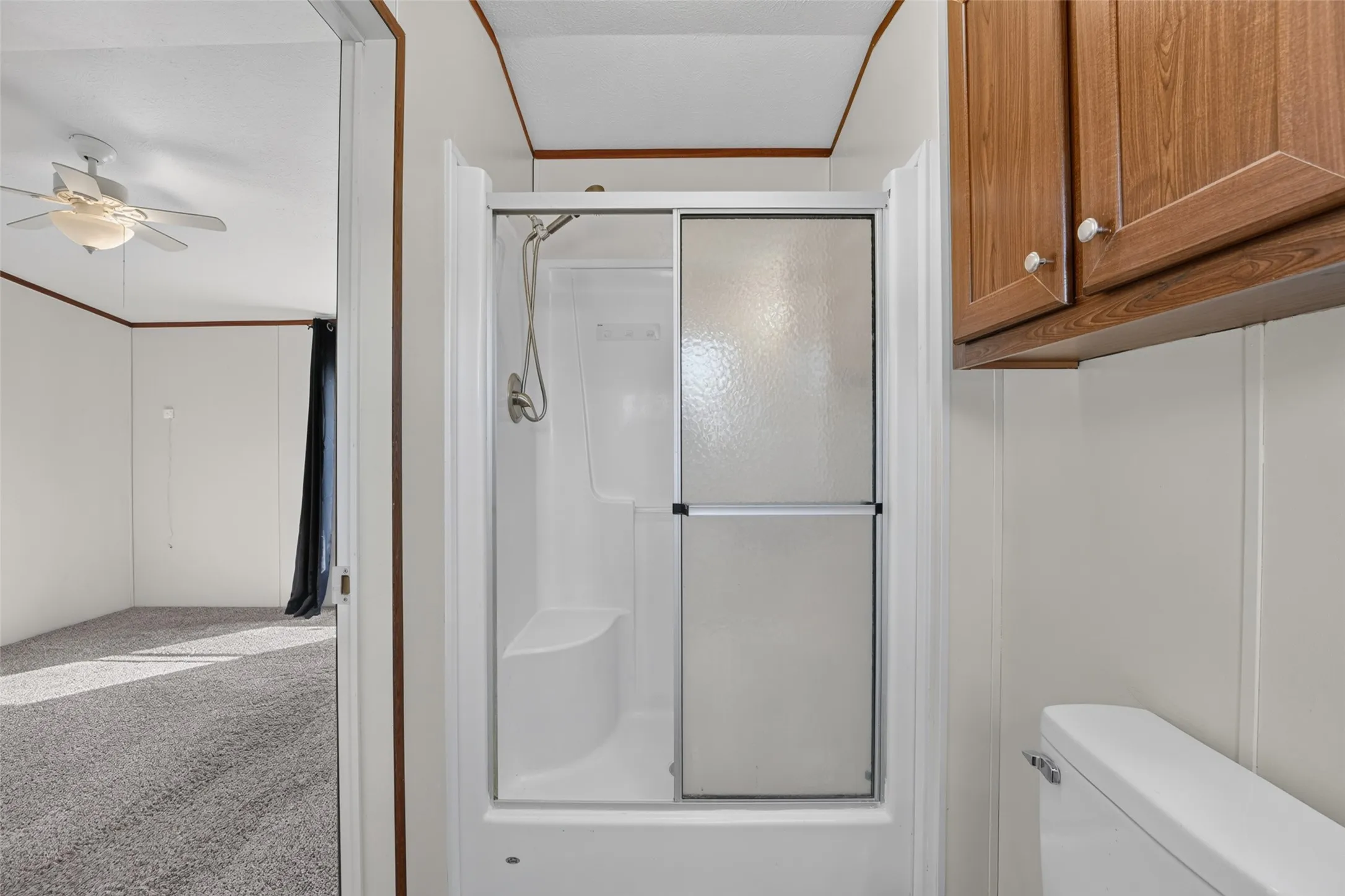 Walk-in shower with sliding glass doors, integrated seating, and a handheld showerhead