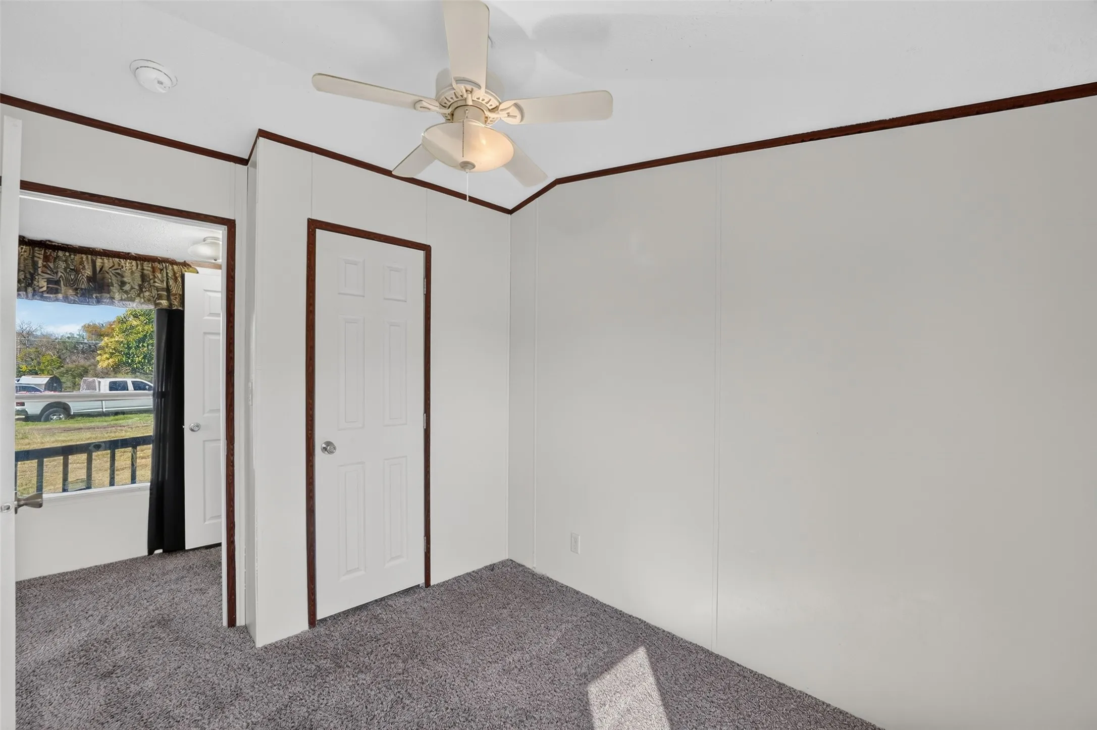 Wall-to-wall carpeting, ceiling fan with integrated lighting, and white paneled walls